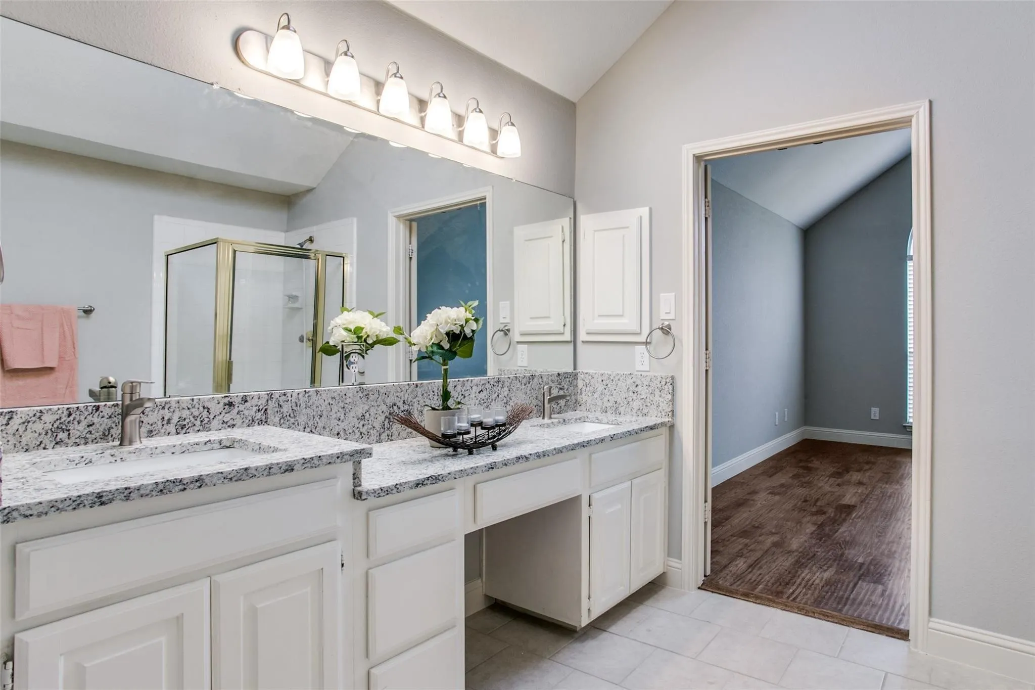 Double vanity with a granite countertop, dual undermount sinks, and white shaker-style cabinetry