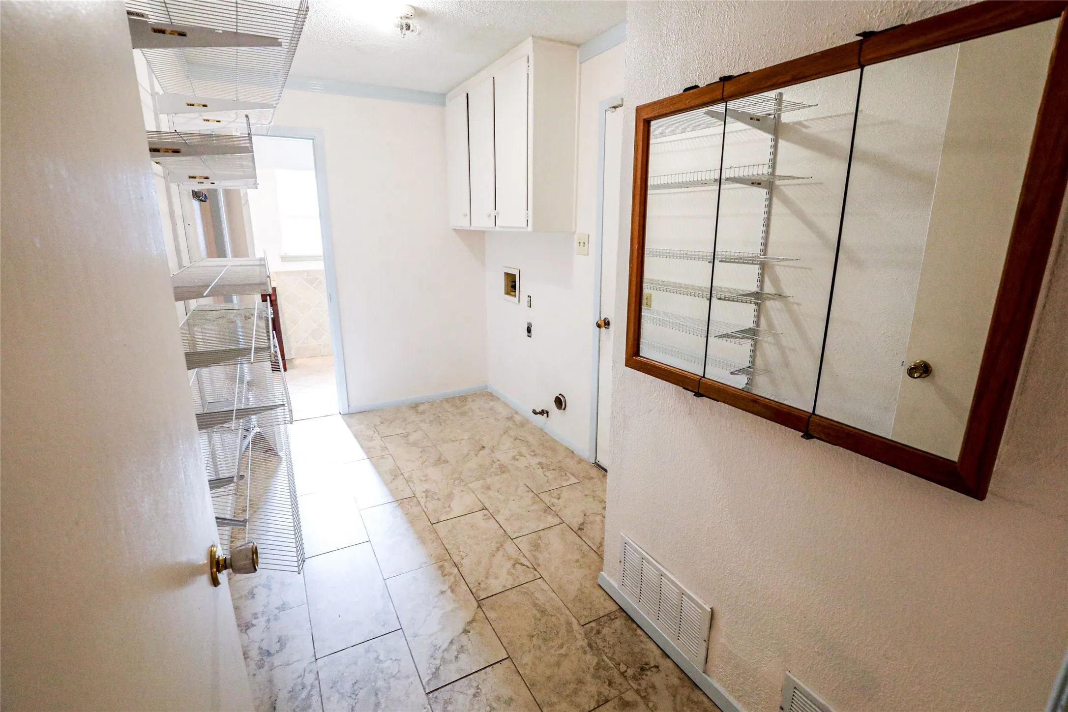 Tile flooring, built-in cabinetry, wall-mounted mirror, and wire shelving