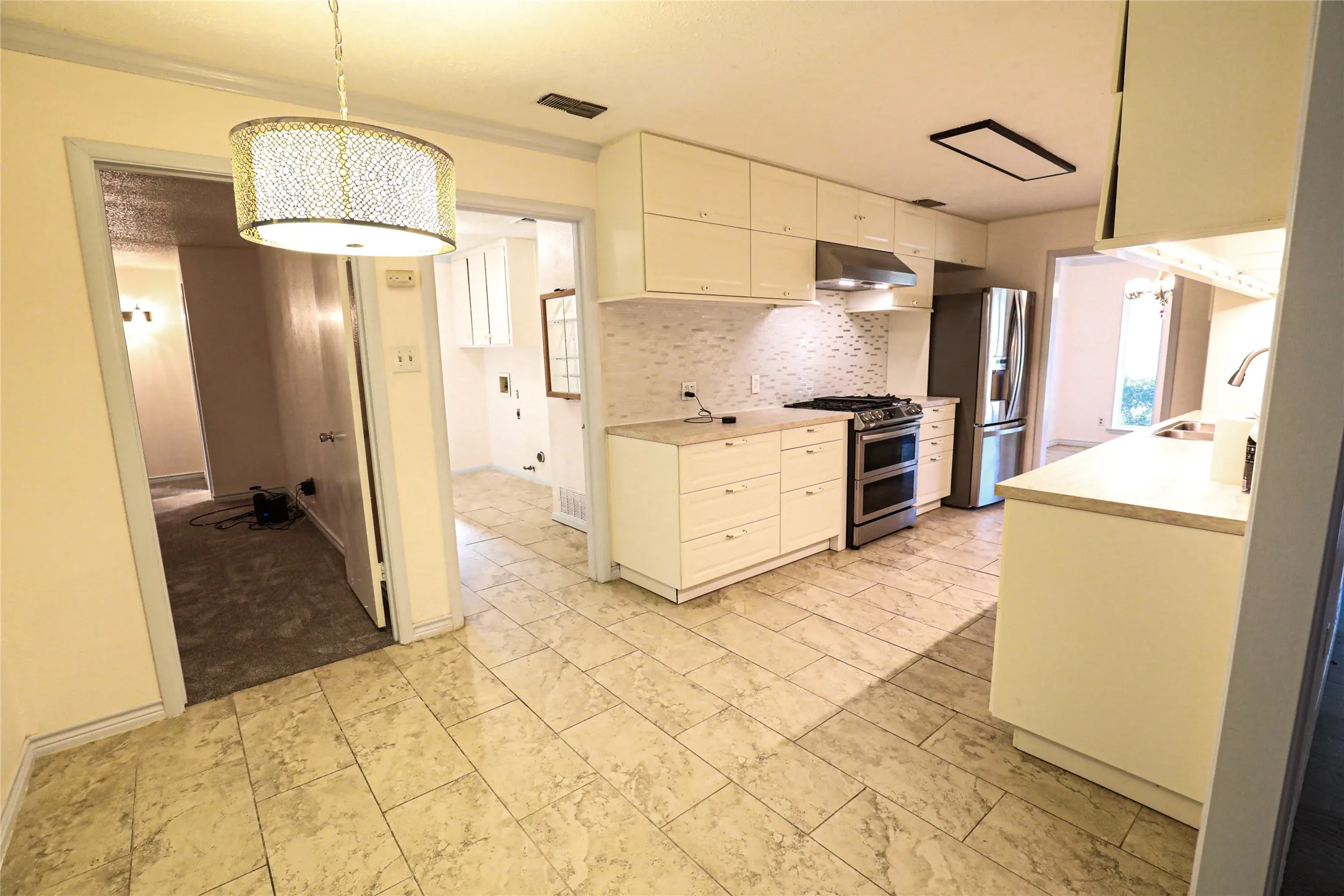 White cabinetry with integrated appliances, tile flooring, and a tile backsplash