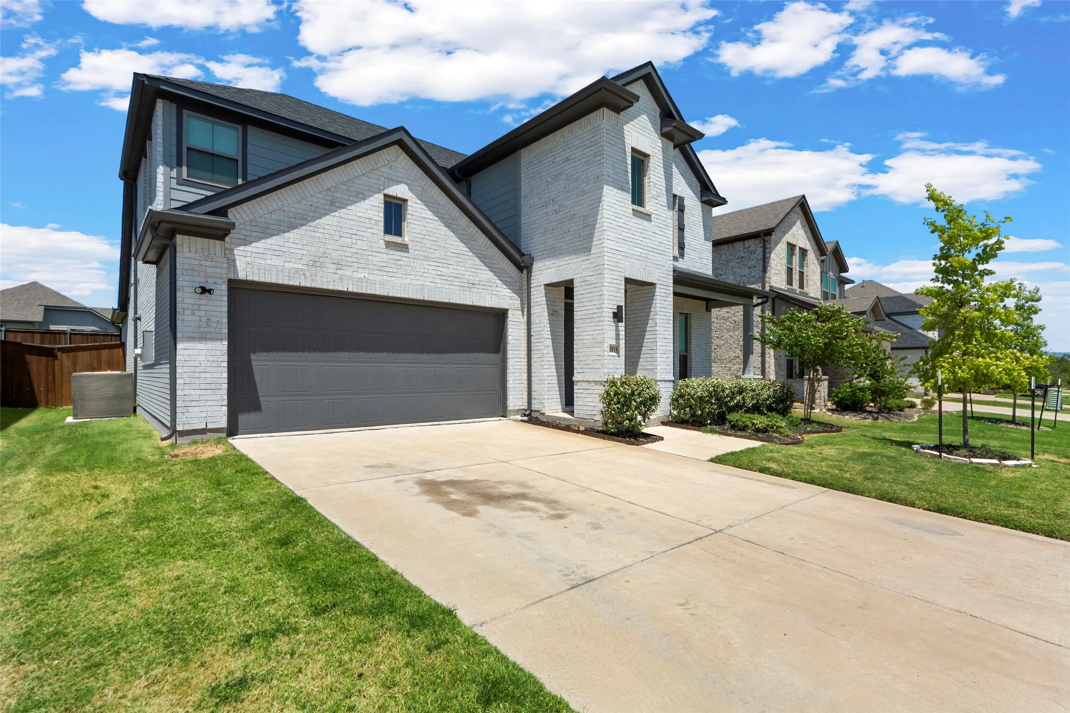 Two-story exterior with light gray brick, dark gray siding accents, and a dark gray garage door