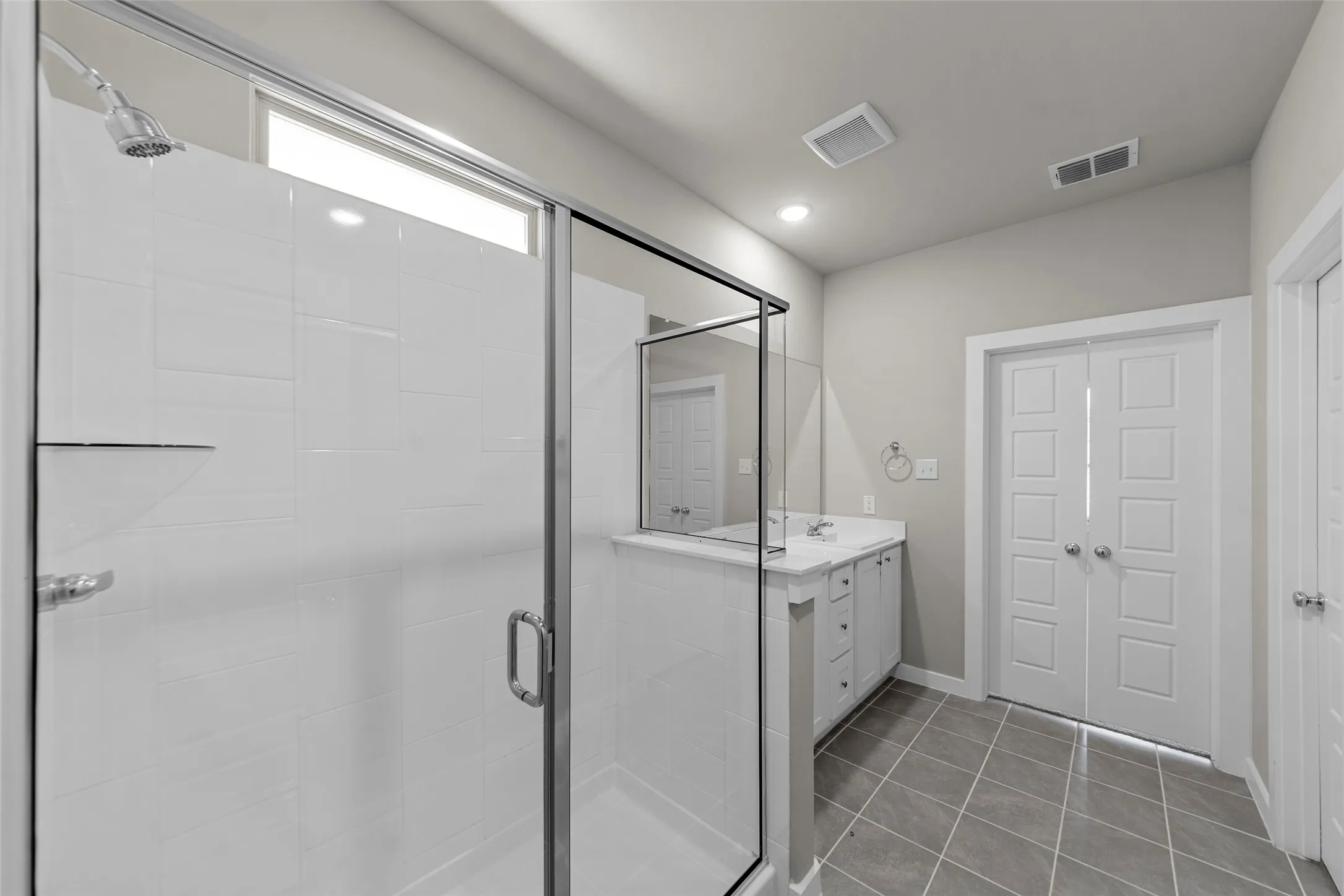 Glass-enclosed shower with a rainfall showerhead and integrated shelving
