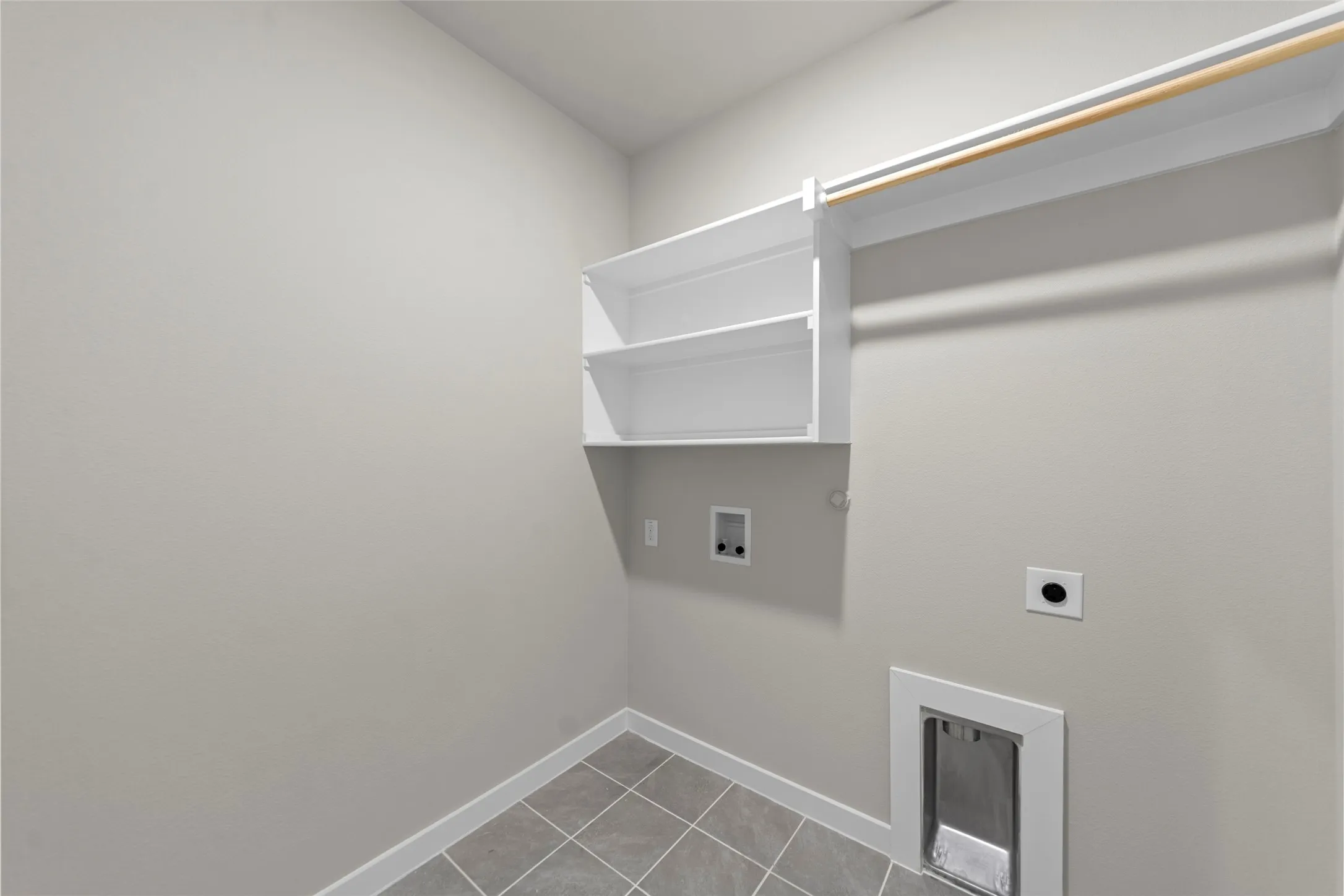 Utility room featuring built-in shelving, a clothes rod, and tile flooring
