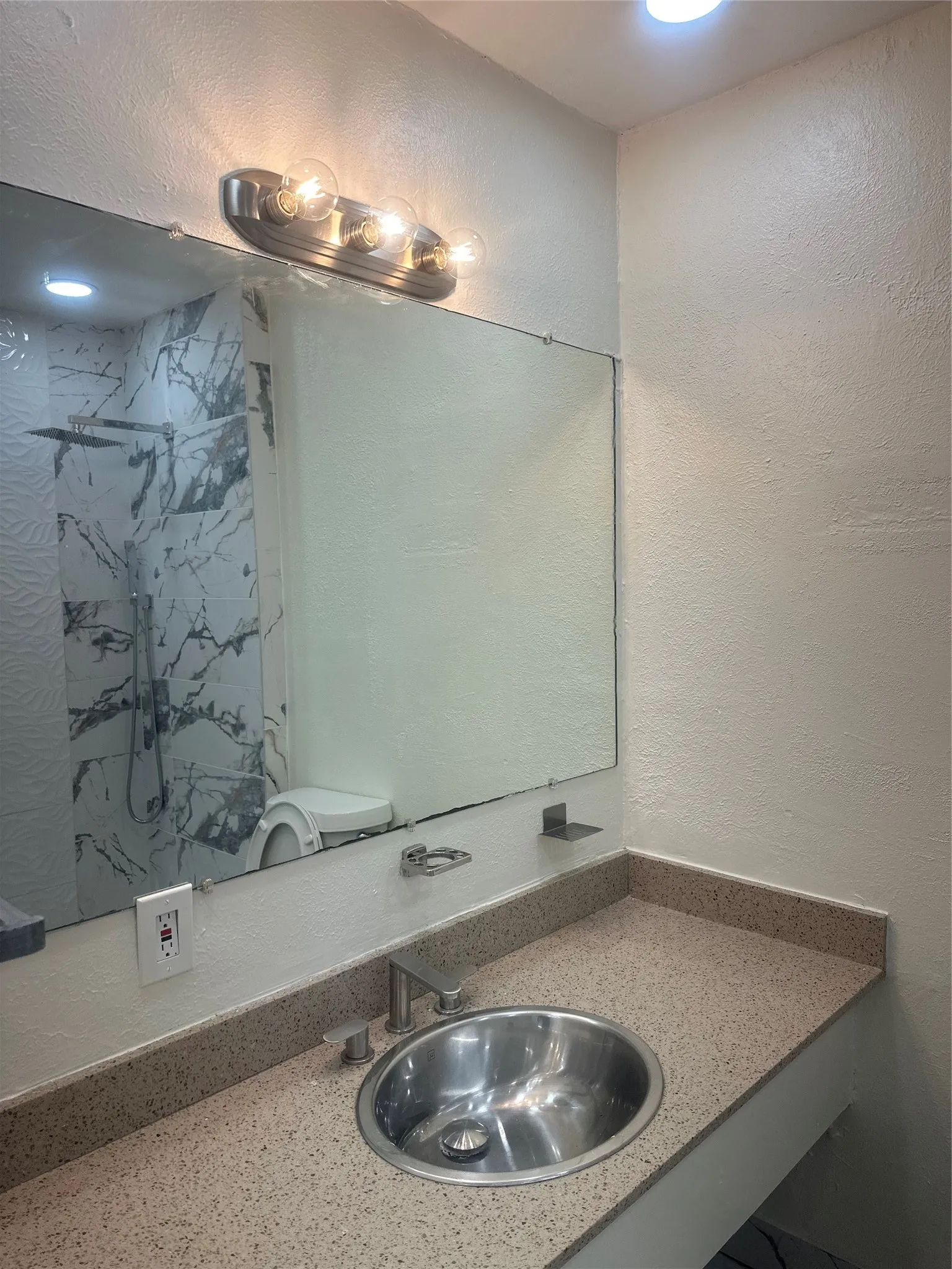 Vanity with an integrated sink, speckled countertop, and a large wall-mounted mirror