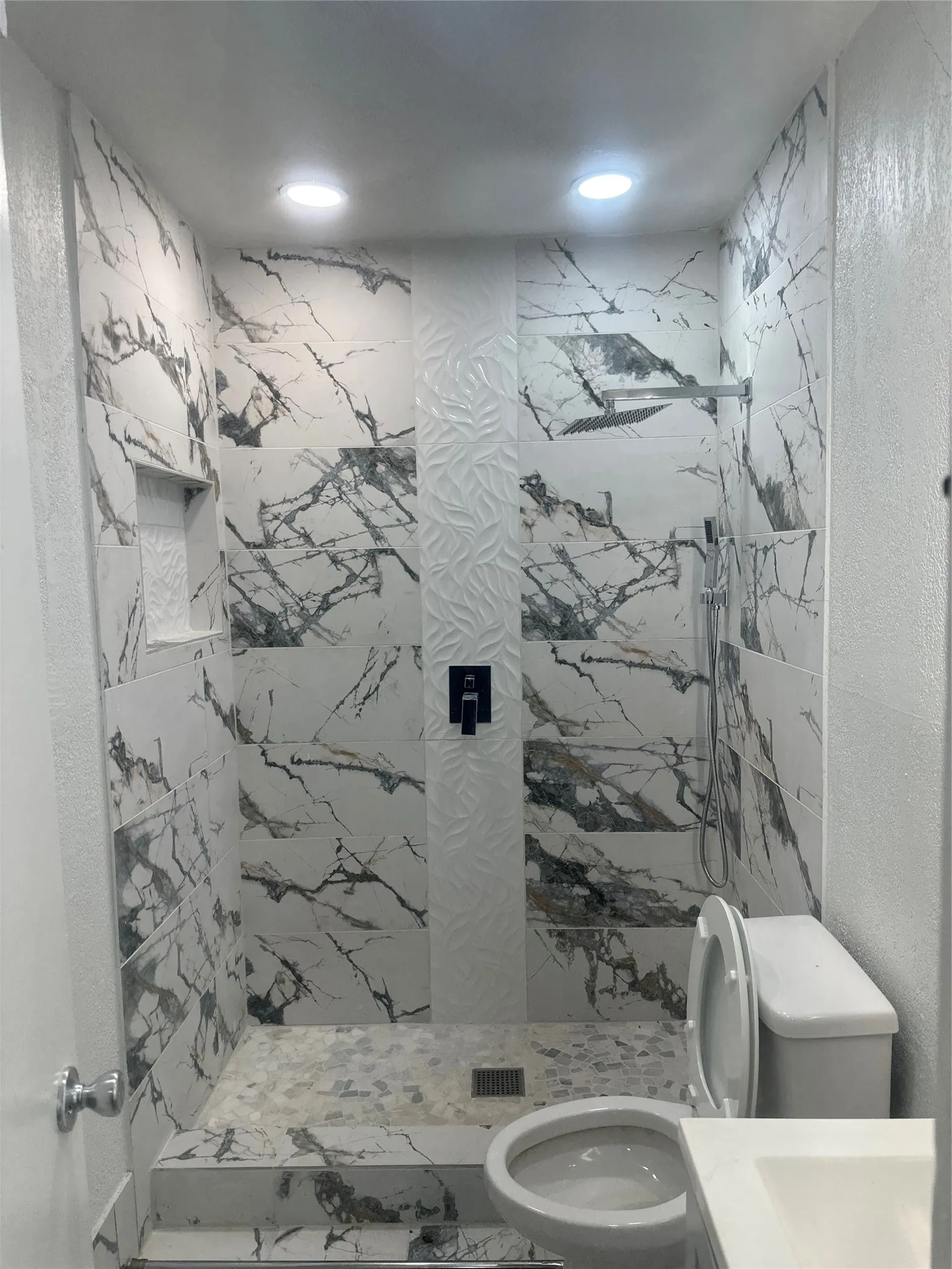 Shower featuring marble-look wall tiling, recessed lighting, and a rainfall showerhead