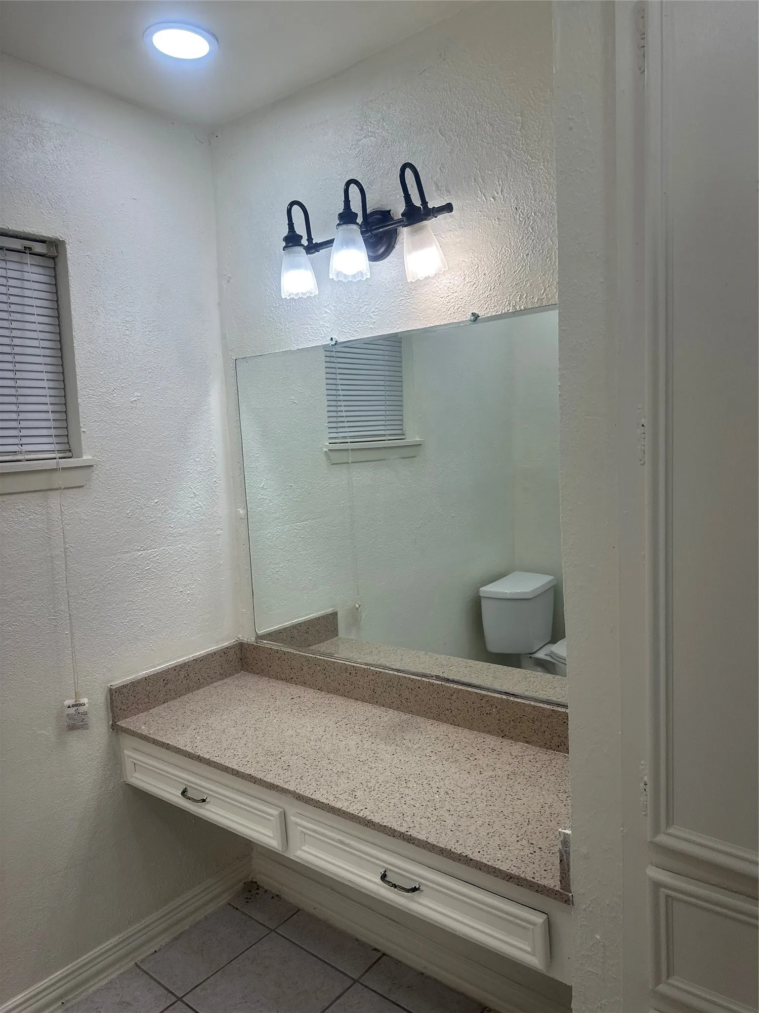 Vanity with a speckled countertop, integrated mirror, and dual drawers