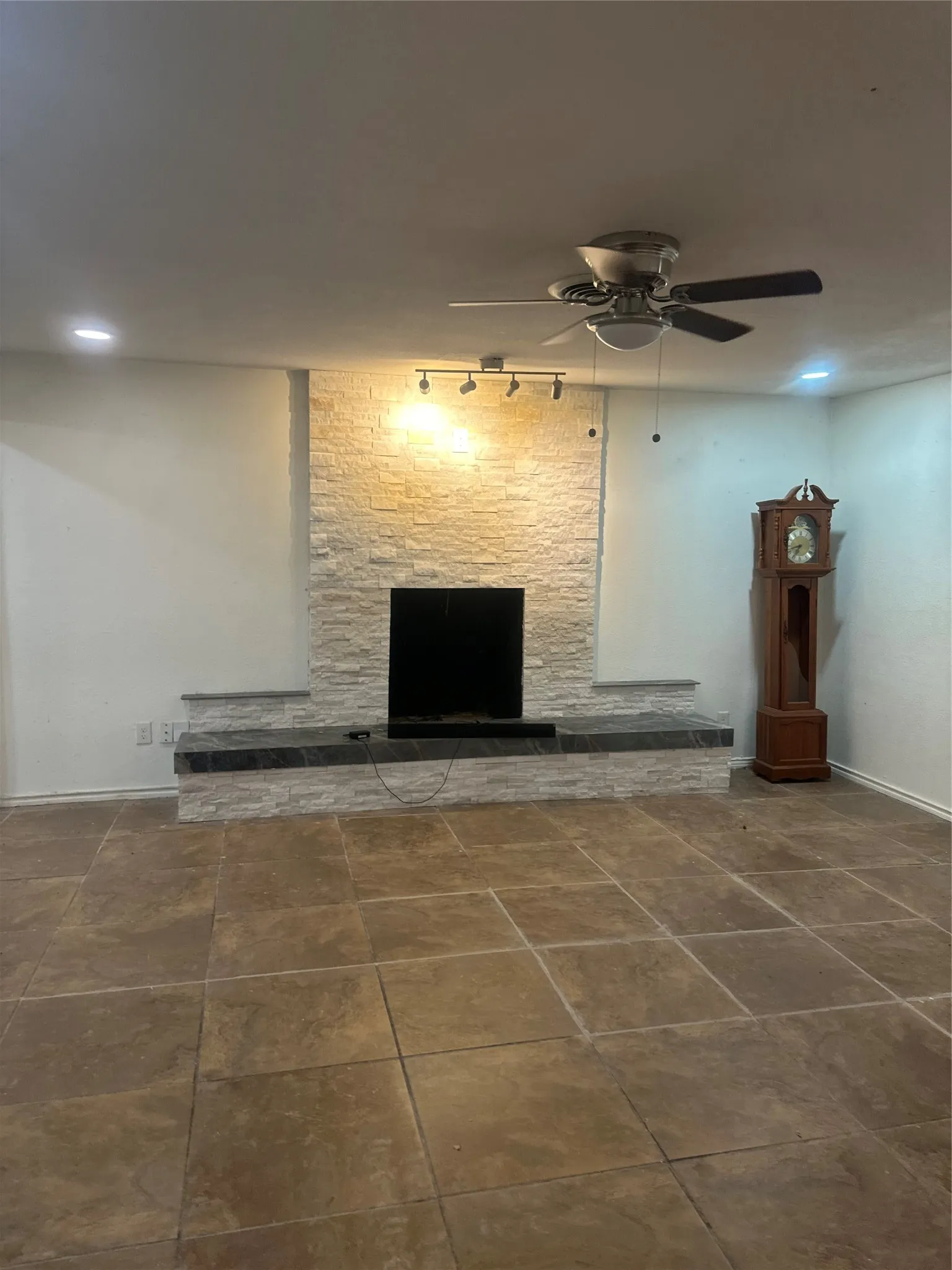 Ceramic tile flooring, fireplace with stone surround, recessed lighting, and a ceiling fan with integrated light