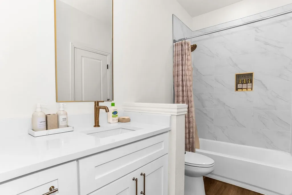 White vanity with a quartz countertop, bronze-finish faucet, and rectangular undermount sink