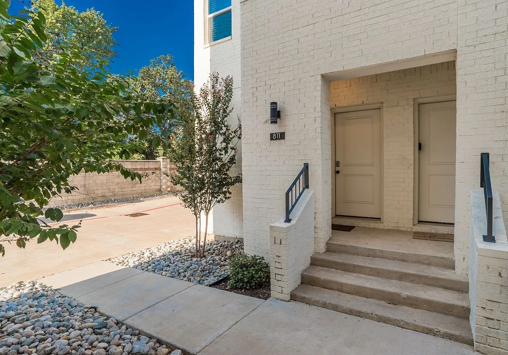 Brick exterior with concrete steps and walkway, accented by decorative river rock landscaping