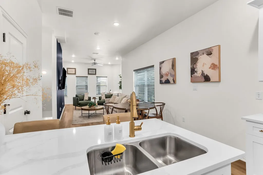 Kitchen island with a double stainless steel sink, gold-tone faucet, and white countertop