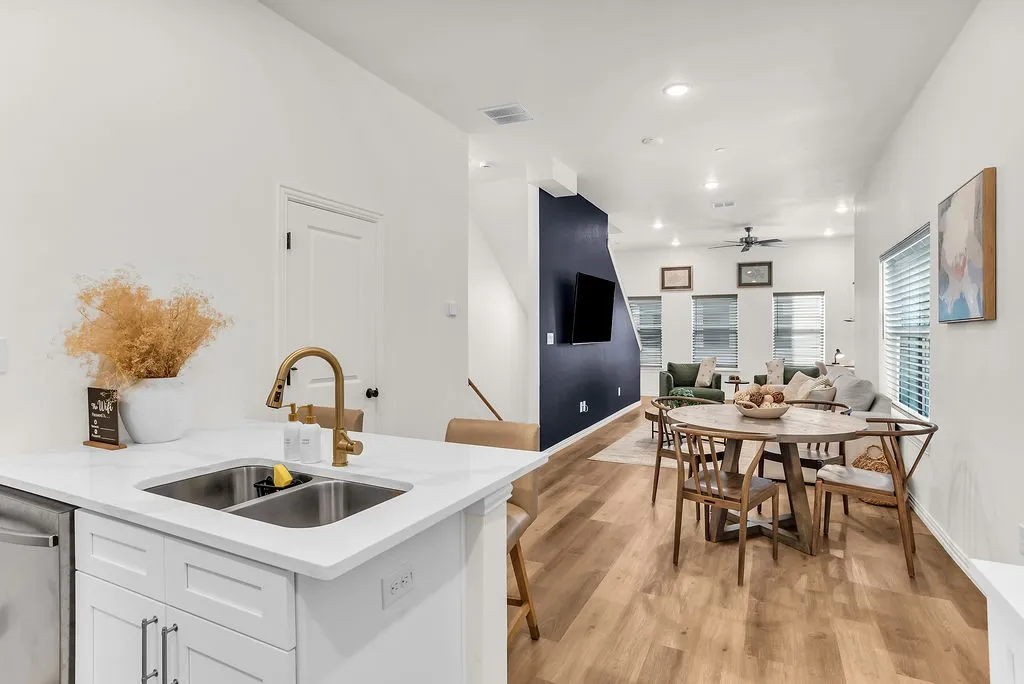 Modern kitchen island featuring a double stainless steel sink, gold-finish faucet, and white countertops