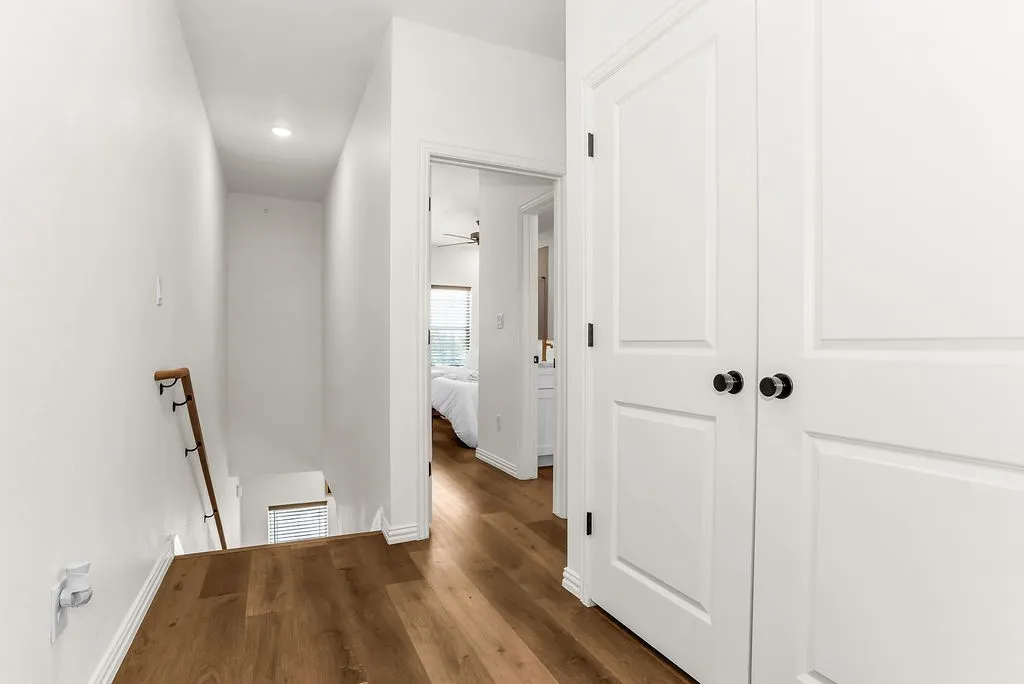 Wood-finish flooring, white paneled doors with black hardware, and recessed lighting