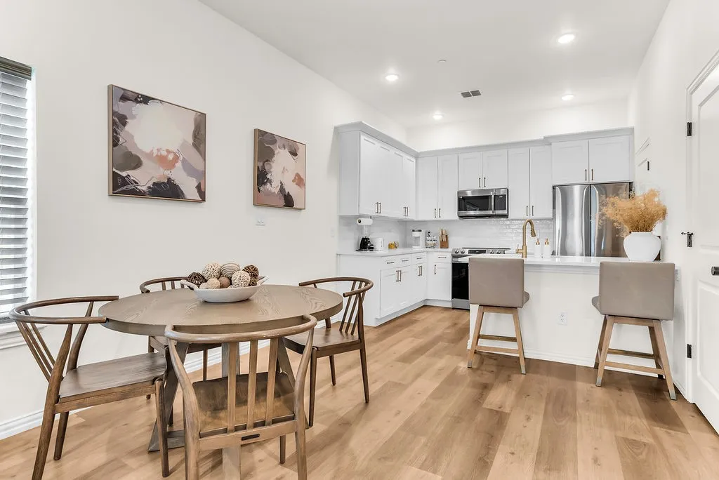 Modern kitchen with white cabinetry, stainless steel appliances, light wood-finish flooring, recessed lighting, and a kitchen island with seating