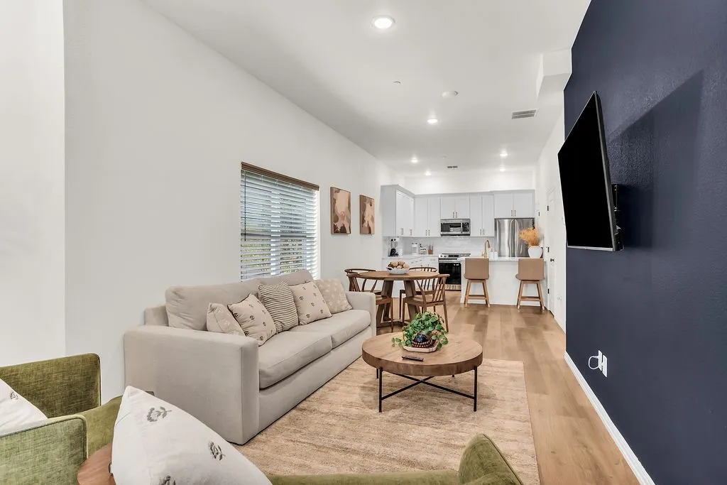 Open concept living space featuring wood-finish flooring, recessed lighting, and a kitchen with white cabinetry and stainless steel appliances