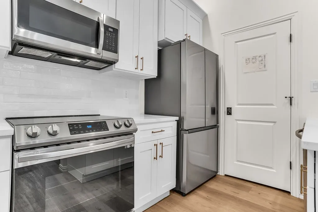 Modern kitchen featuring stainless steel appliances including a slide-in range with convection oven, over-the-range microwave, and French-door refrigerator