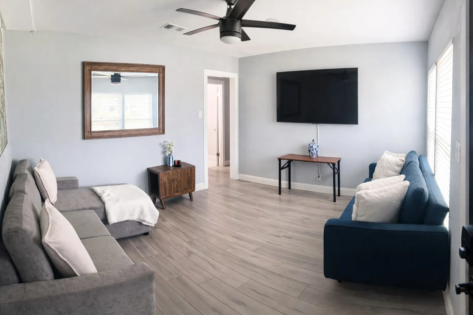 Light wood-finish flooring throughout, ceiling fan with integrated lighting, and white trim