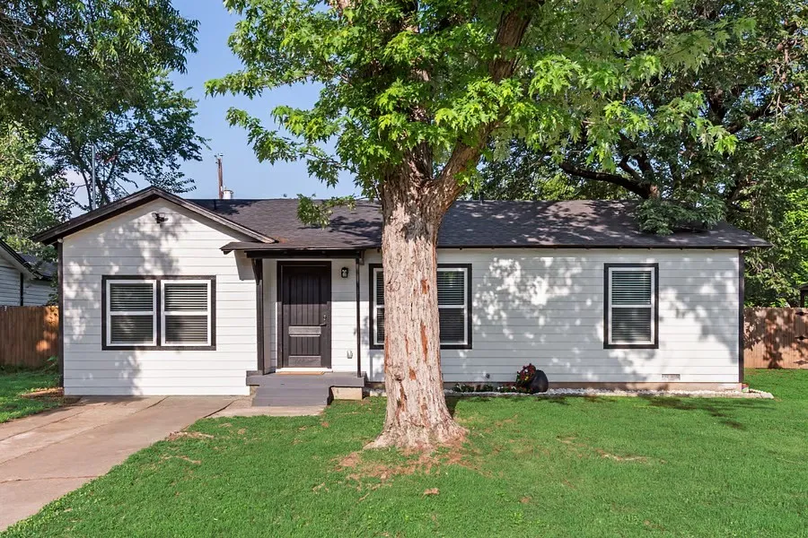 White siding exterior with dark trim accents, a front porch entry, and a dark asphalt shingle roof