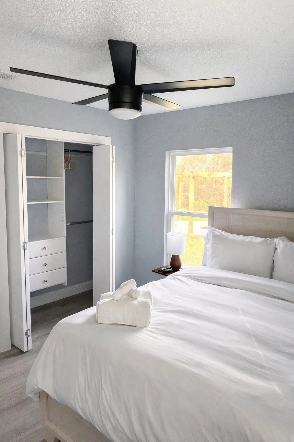 Wood-finish flooring, built-in closet organization, contemporary ceiling fan, and a large window
