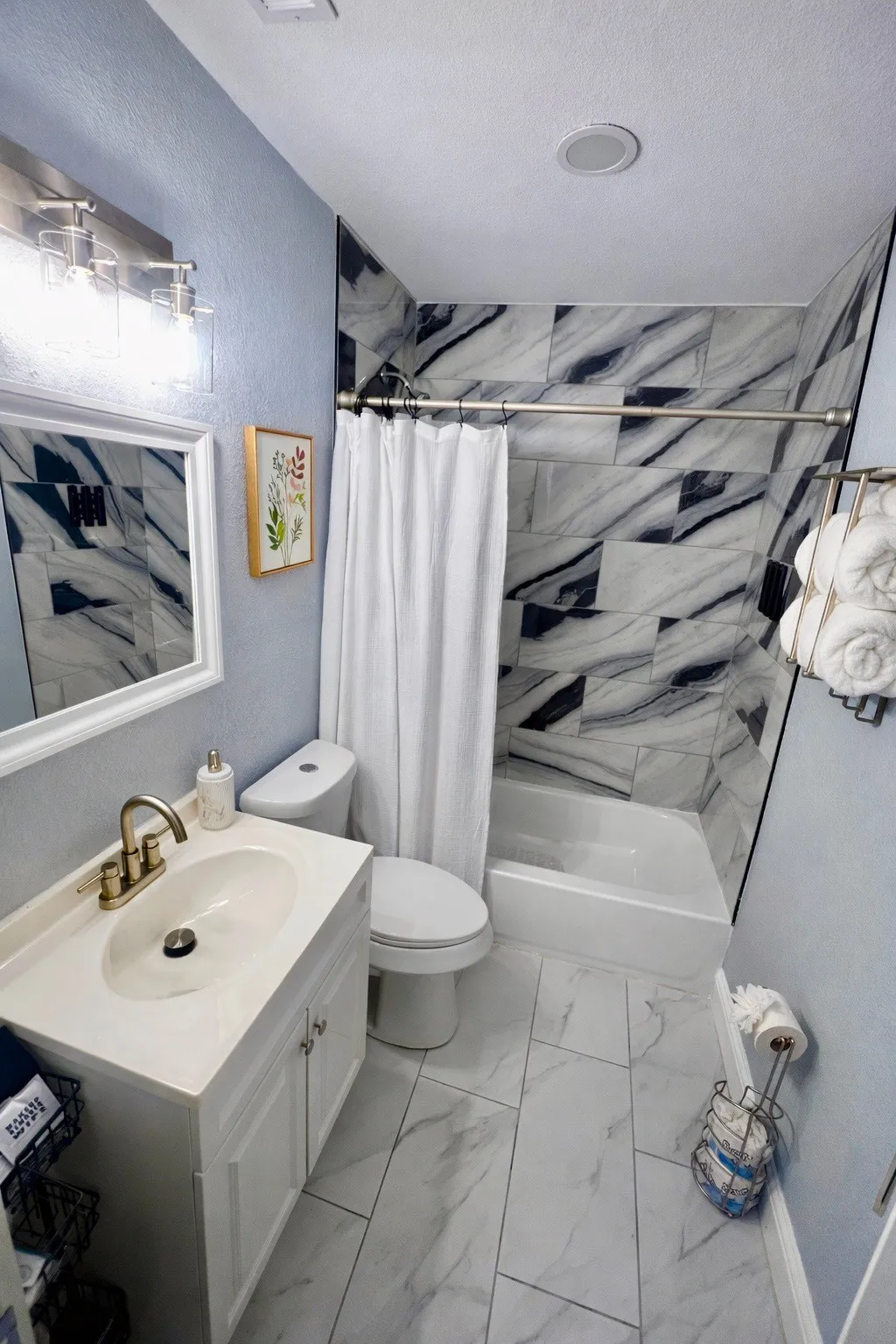Vanity with integral sink, tub with tile surround, toilet, and tile flooring