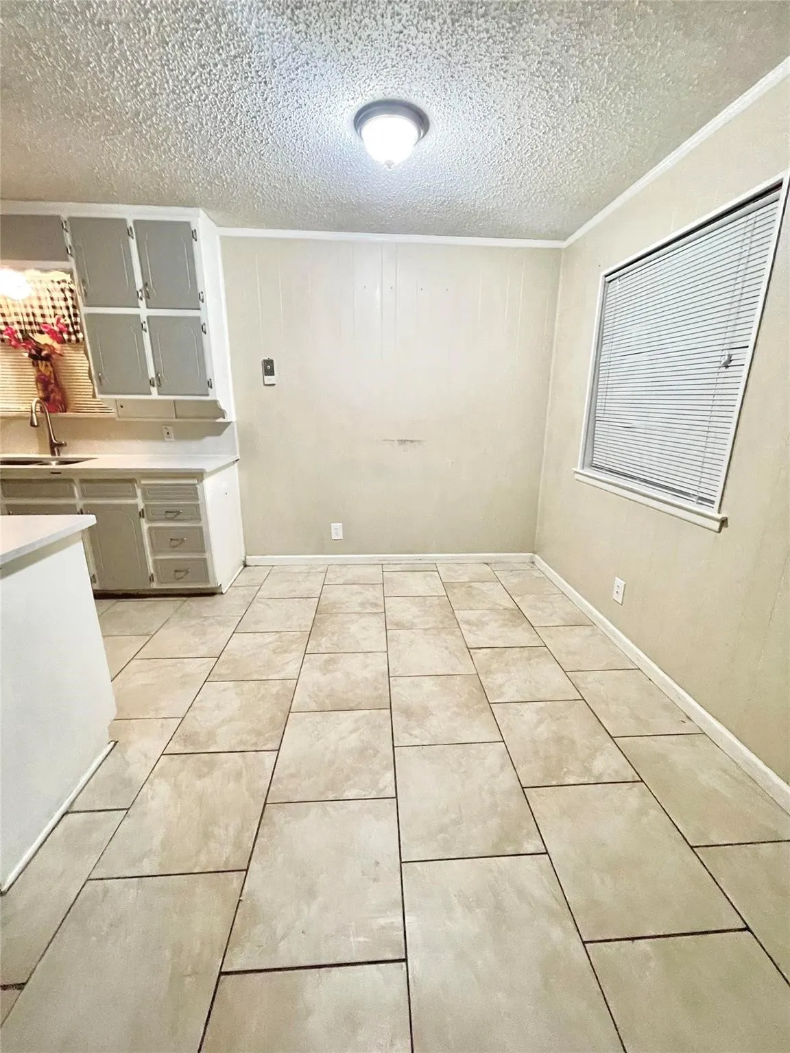 Unfurnished dining area with light tile patterned floors, a textured ceiling, crown molding, and sink