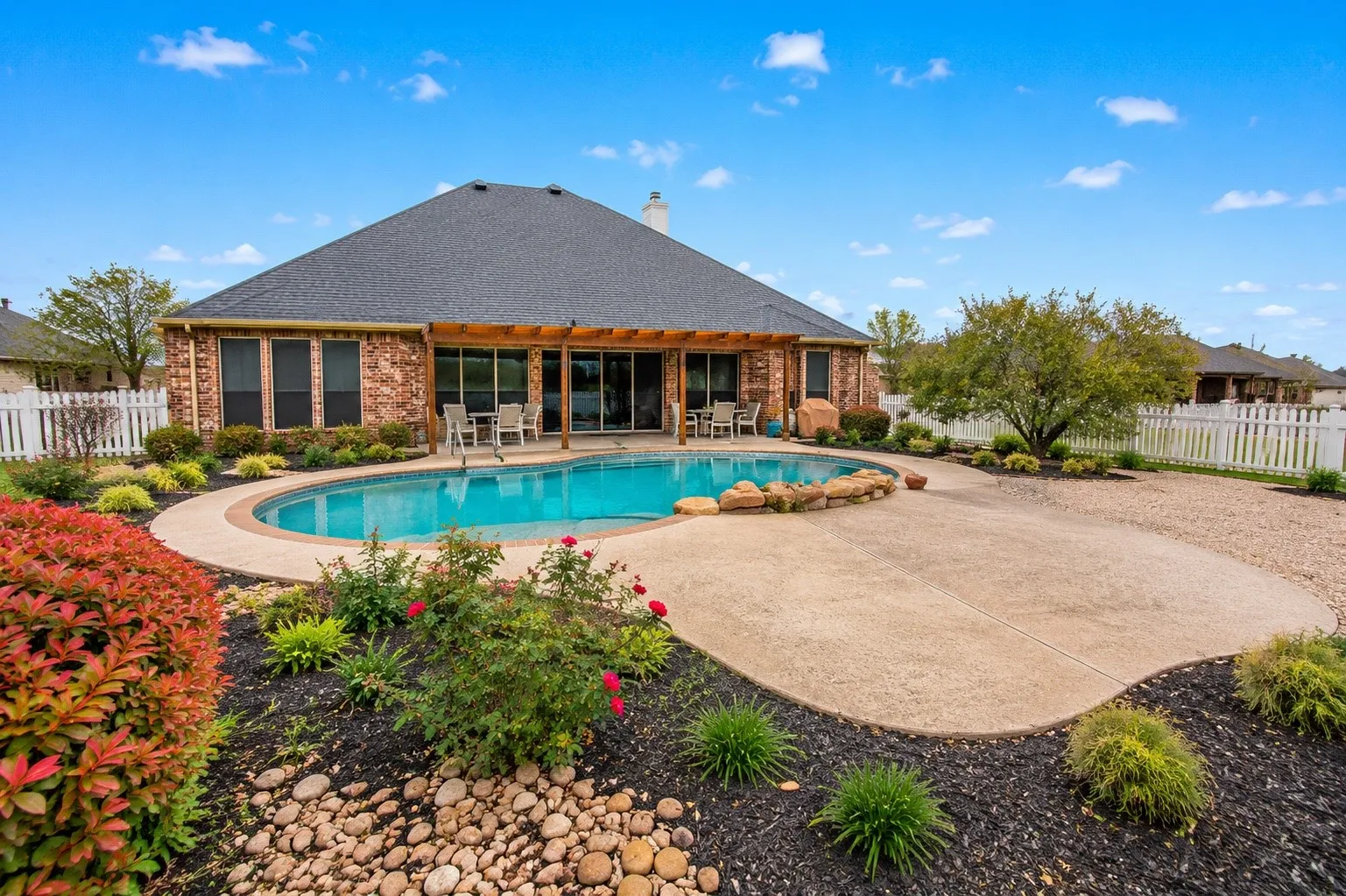 Custom-shaped swimming pool with an expansive concrete patio and surrounding landscape