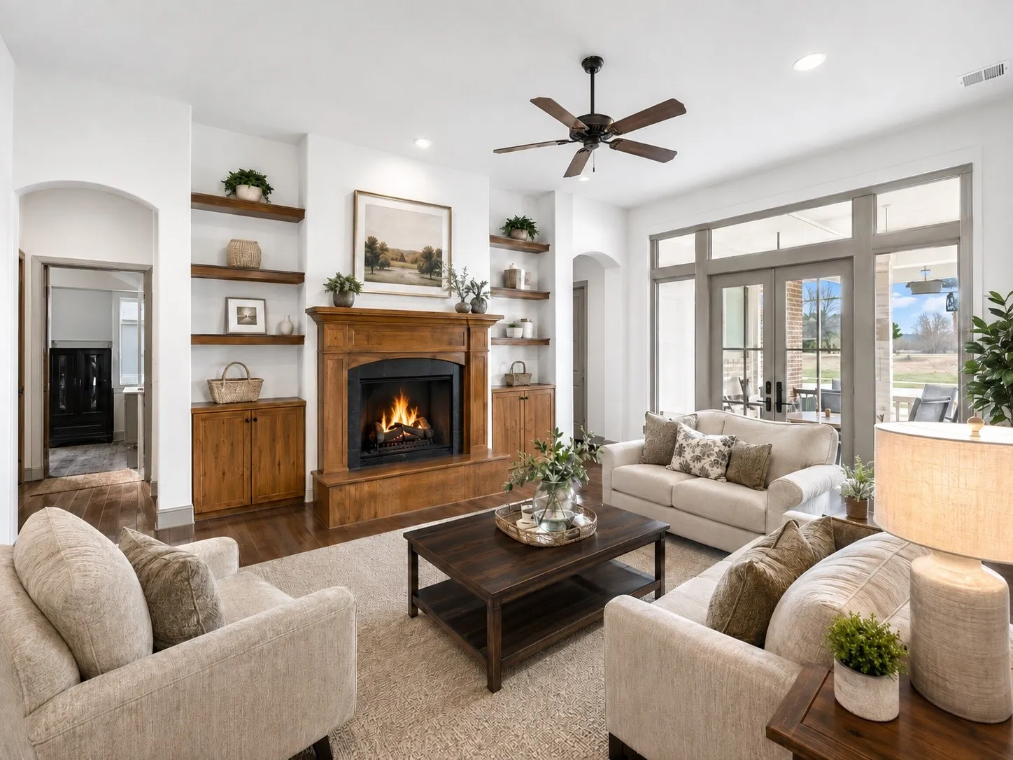 Living area with fireplace featuring a wood mantel, built-in shelving, wood-finish flooring, and double glass-paneled doors with transom windows