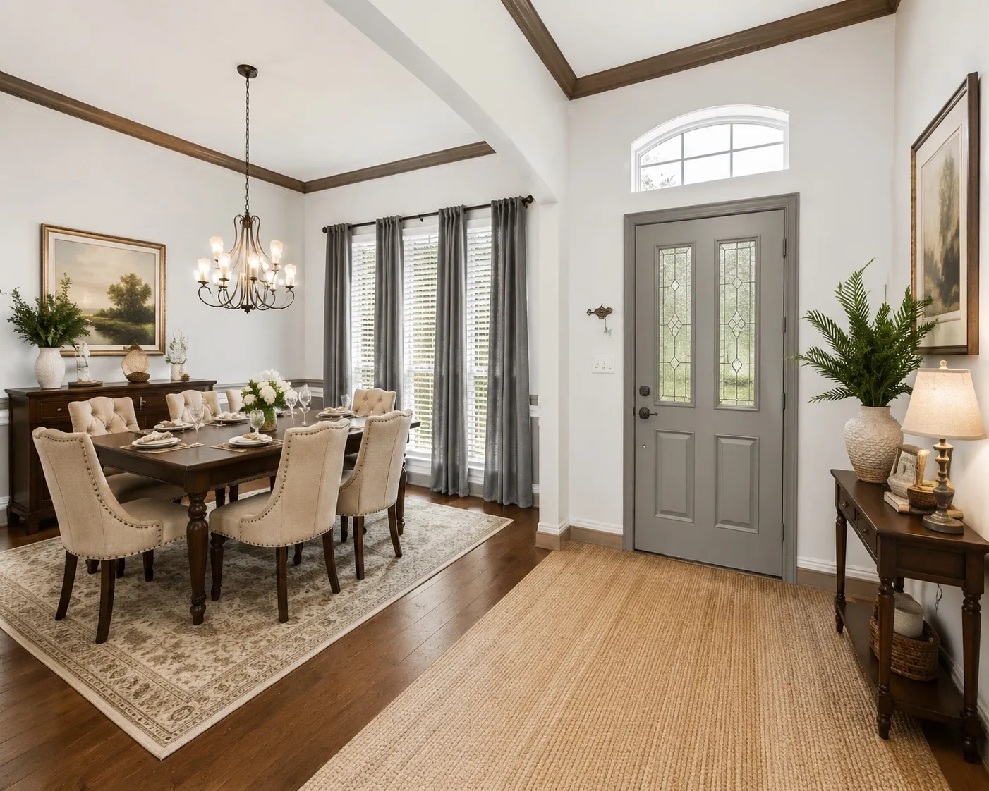 Hardwood flooring, tray ceiling with wood-finish trim, chandelier lighting fixture, decorative front door with leaded glass inserts, and arched transom window