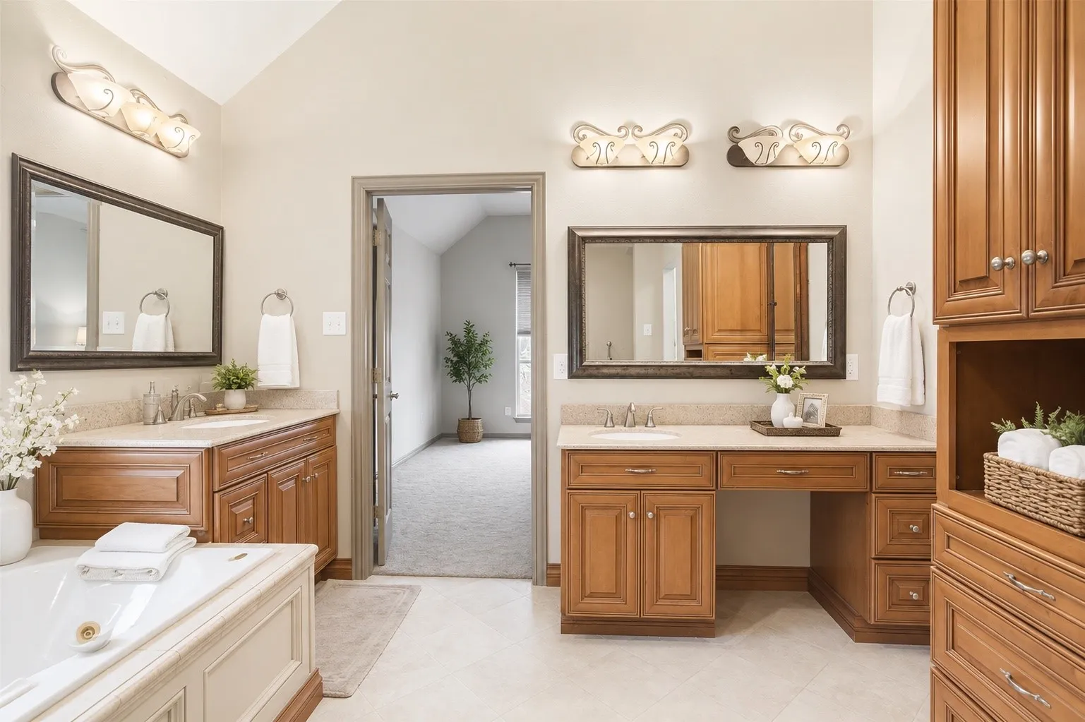 Dual vanity sinks with under-cabinet storage, a built-in vanity desk, and a large soaking tub