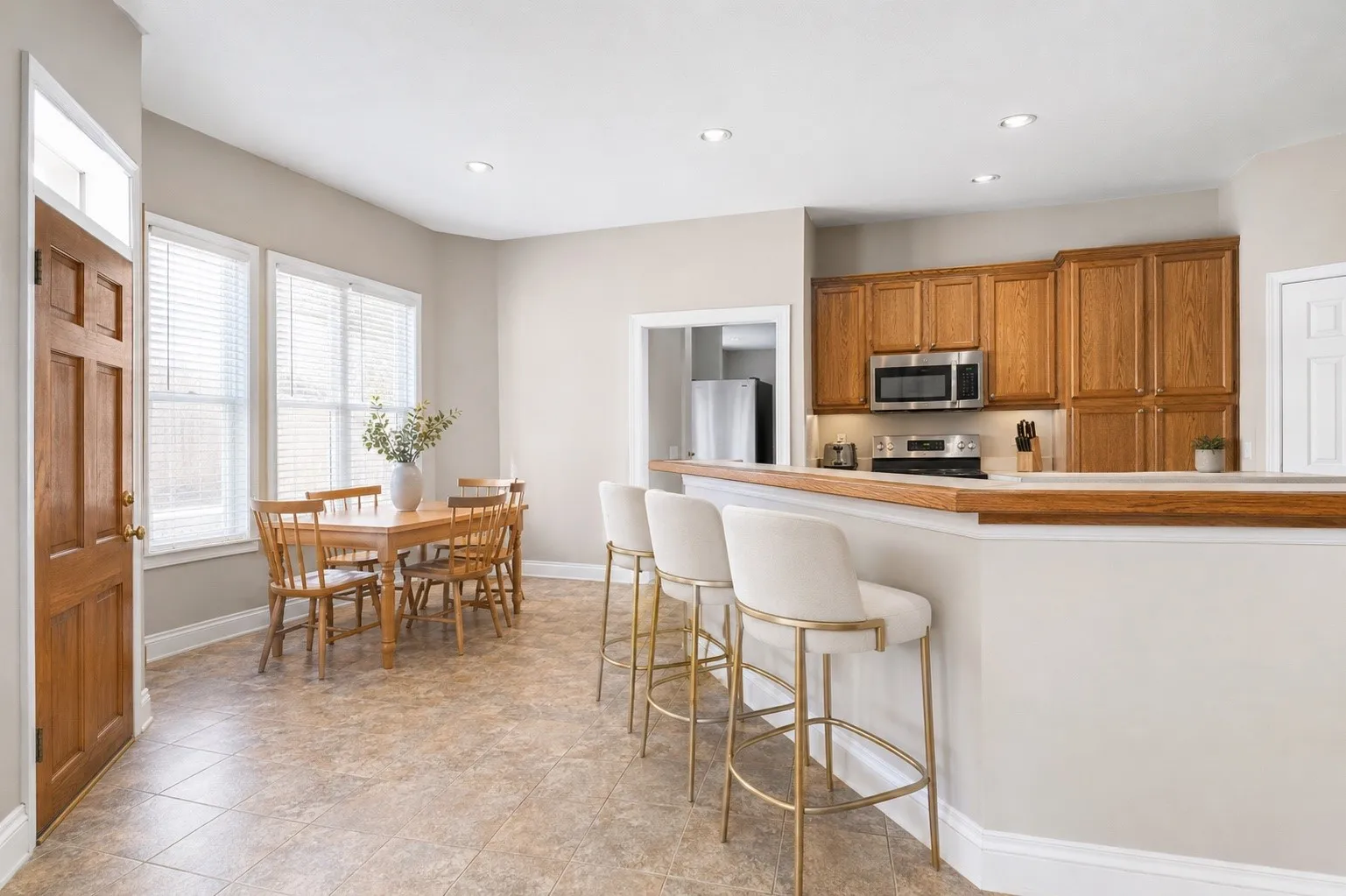 Kitchen and dining area featuring wood-finish cabinetry, stainless steel microwave, tile flooring, and recessed lighting