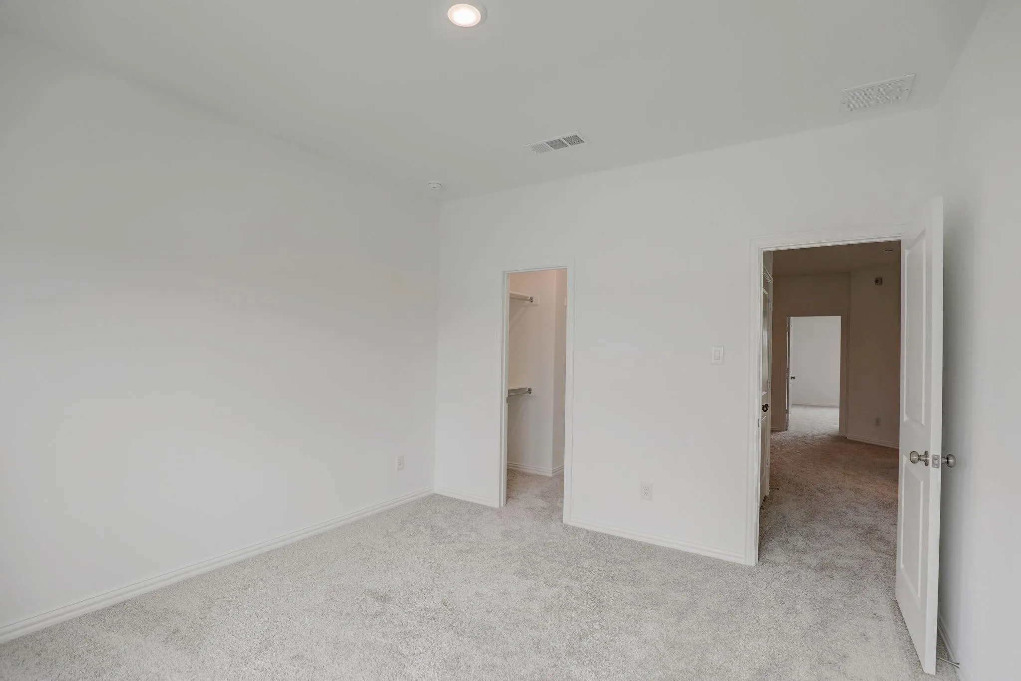 Recessed ceiling lighting, light gray wall-to-wall carpeting, white interior doors with chrome hardware, and an integrated closet system