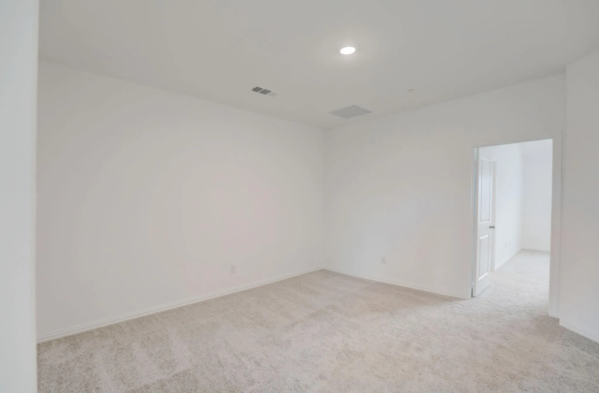 Recessed lighting, light-toned carpeting, white walls, and a white interior door