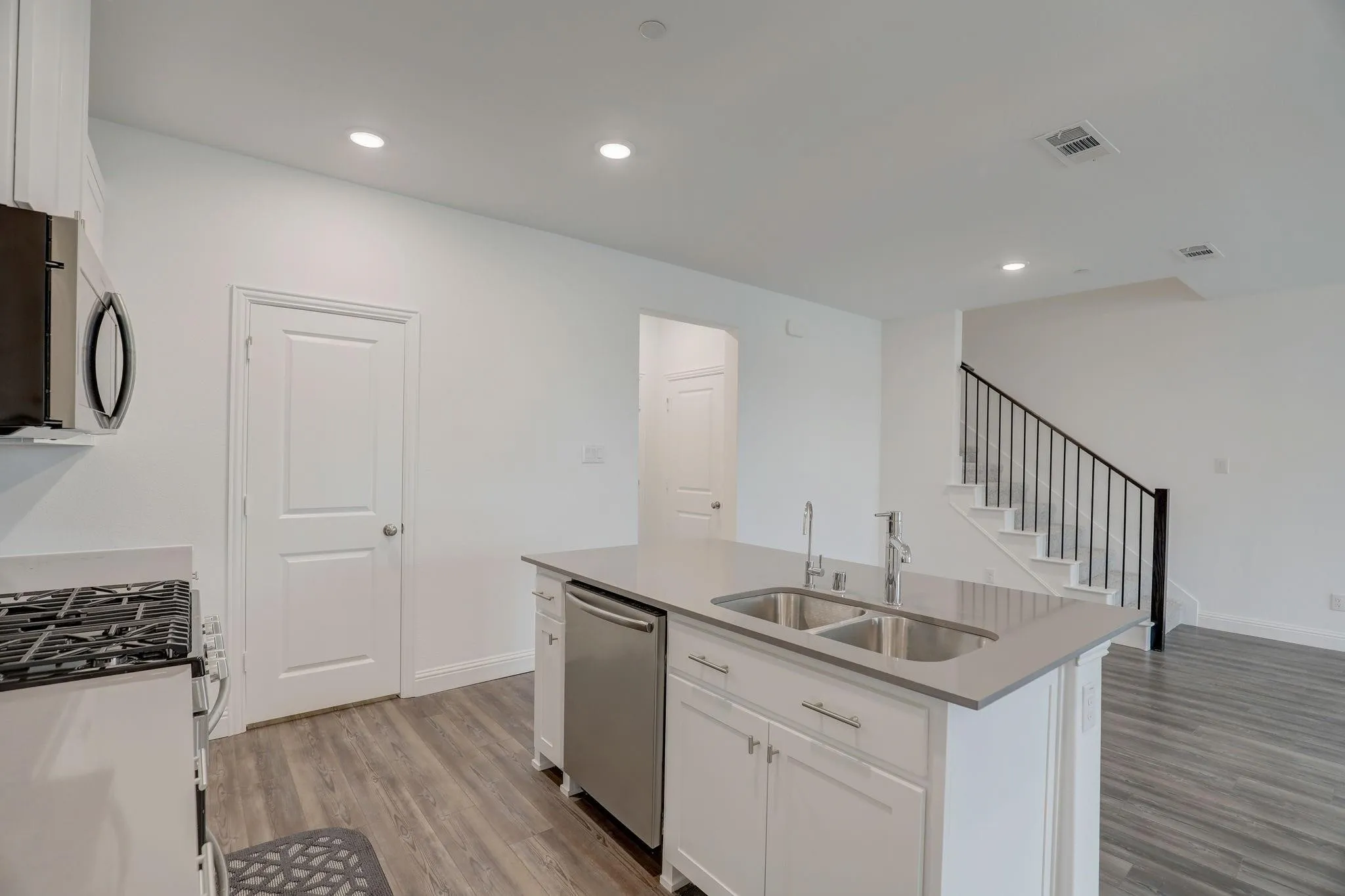 Kitchen island featuring an undermount double sink, stainless steel dishwasher, and light-toned countertop