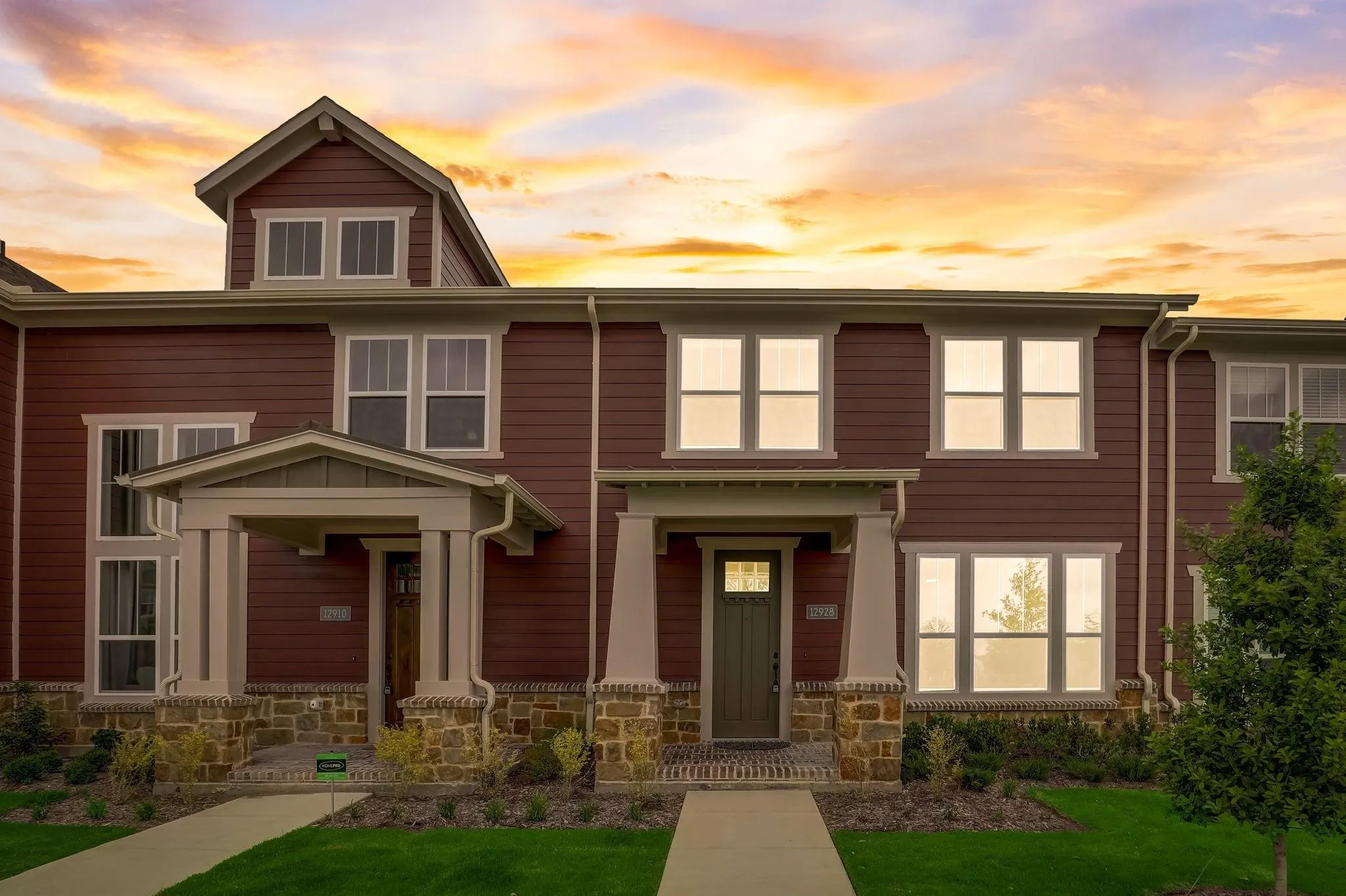 Siding exterior with multiple windows and a covered entry, featuring stone column bases