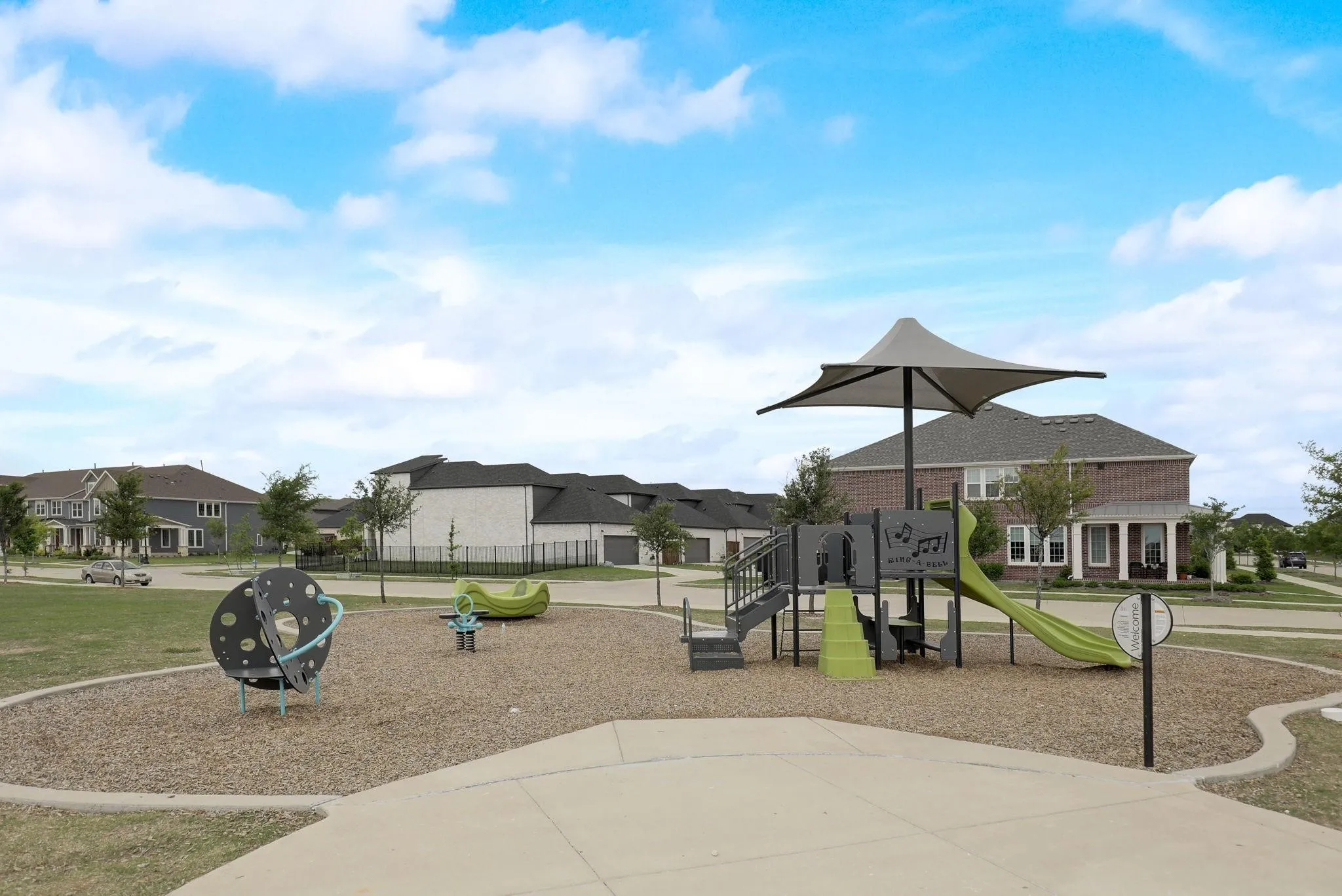 Neighborhood park with play structures, shade canopy, and surrounding residential properties