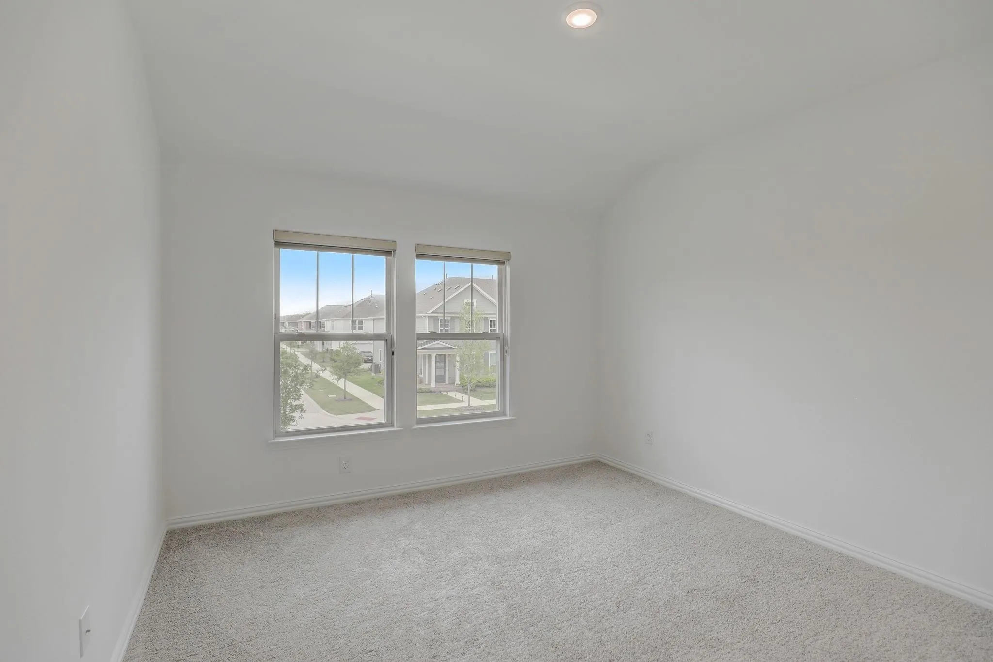 Neutral-toned walls, recessed ceiling lighting, light gray carpet, and two double-hung windows