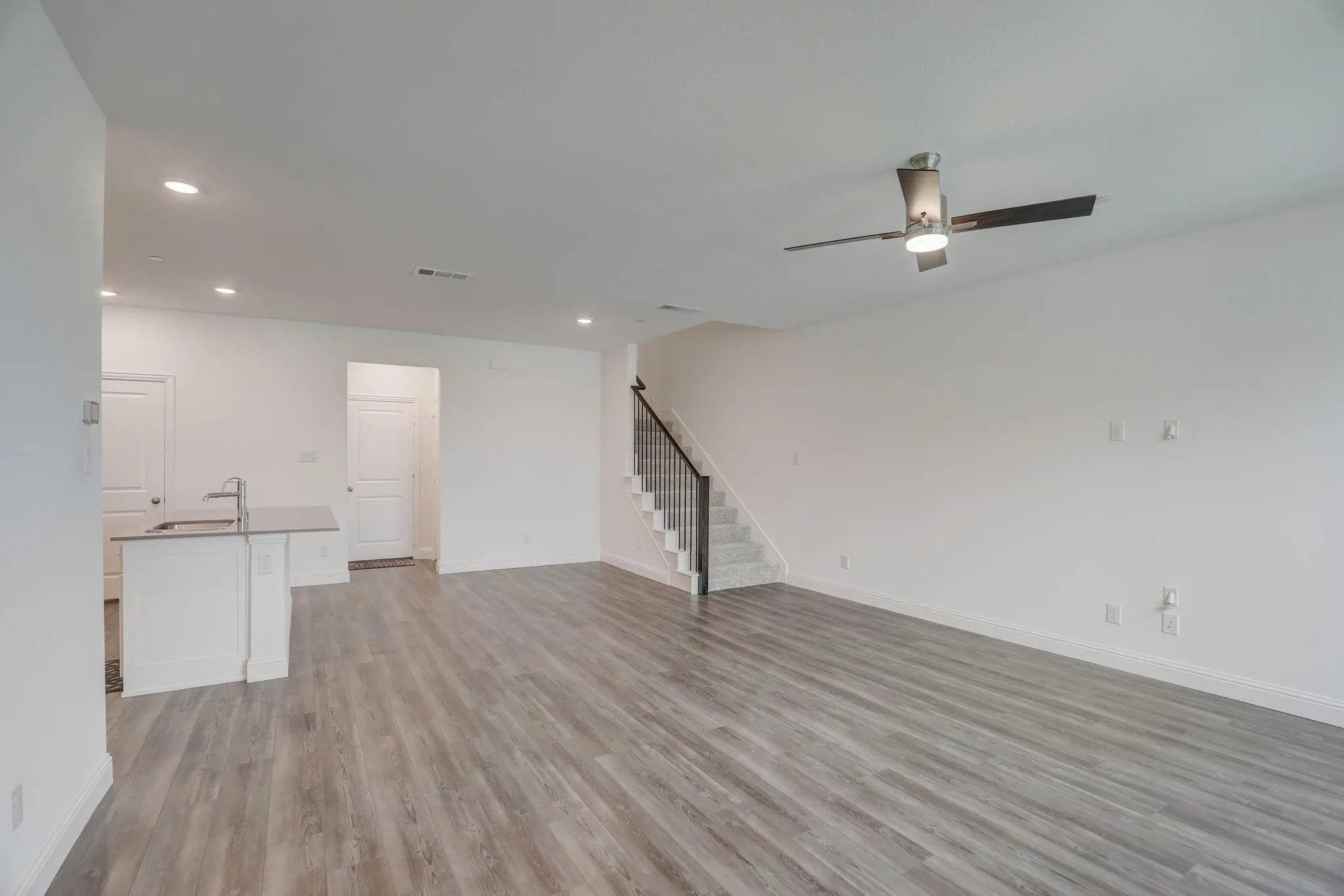 Open-concept living space featuring wood-finish flooring, recessed lighting, and a contemporary ceiling fan