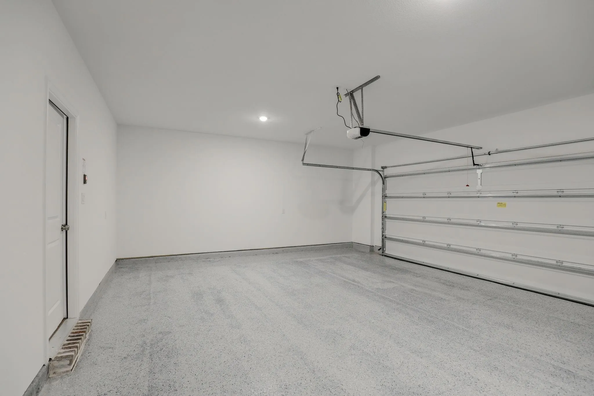 Attached garage with a white overhead door and automatic opener