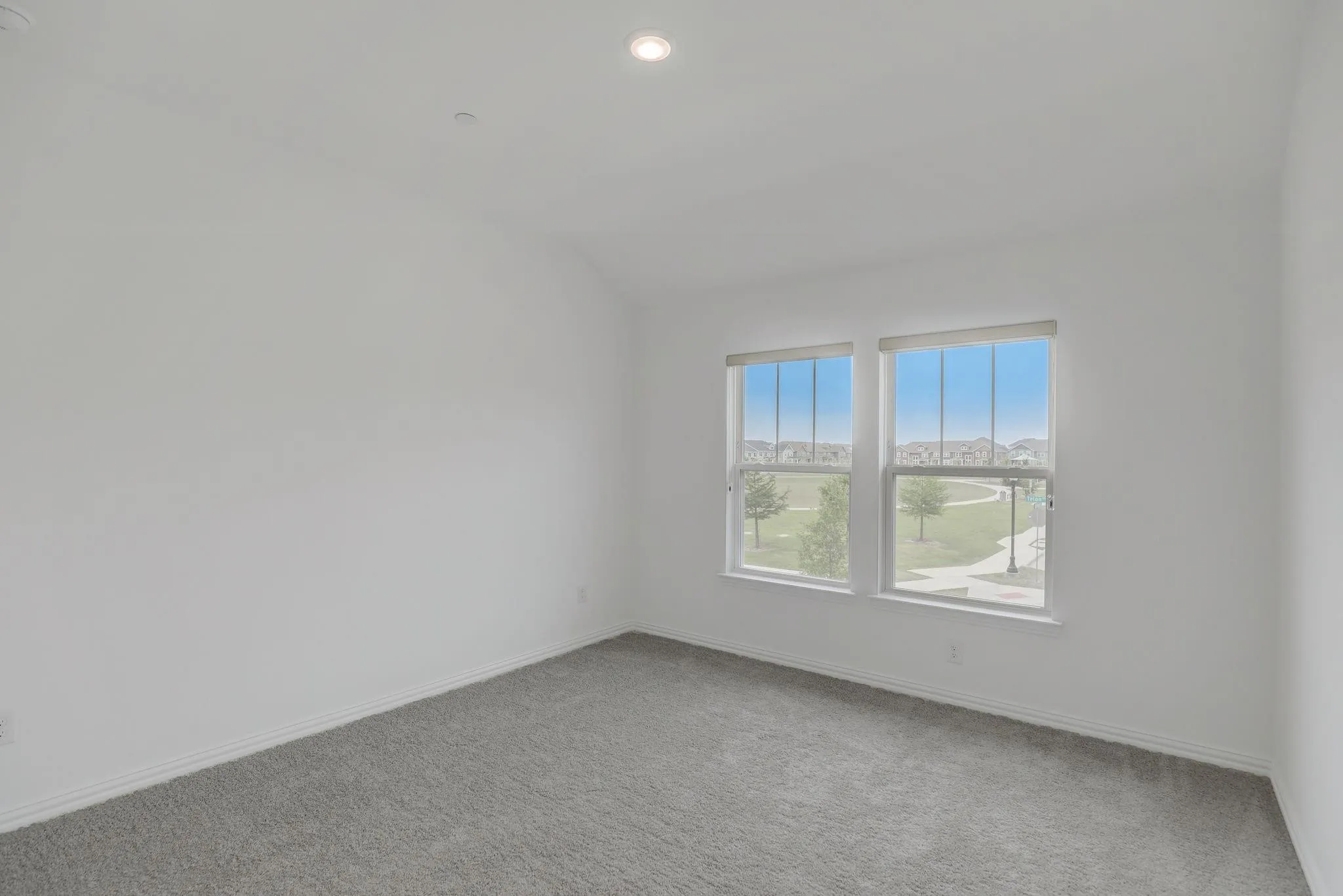 Recessed lighting, white walls, gray carpet, and two windows