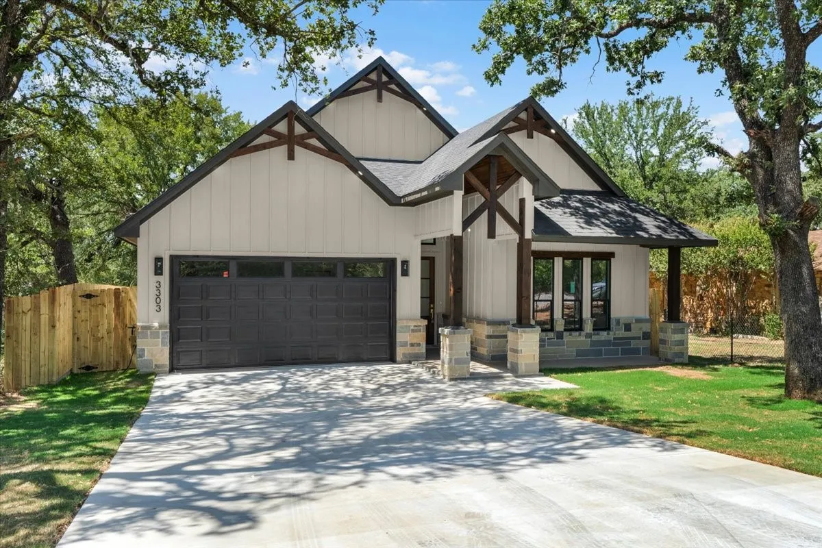 Modern farmhouse exterior with board and batten siding, stone accents, and a dark asphalt shingle roof