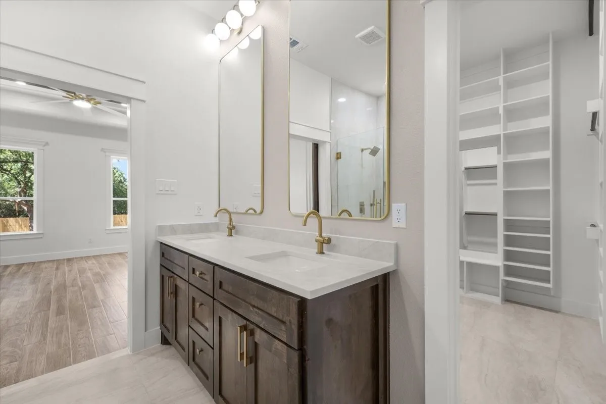 Dual vanity with undermount sinks, gold-finish fixtures, and a shower with glass enclosure