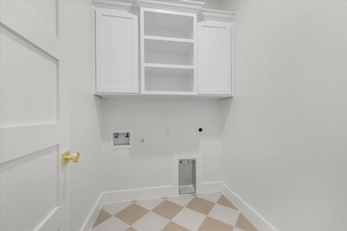 White shaker-style cabinetry with crown molding, checkered floor tiling, and a panel-style door with a brass knob