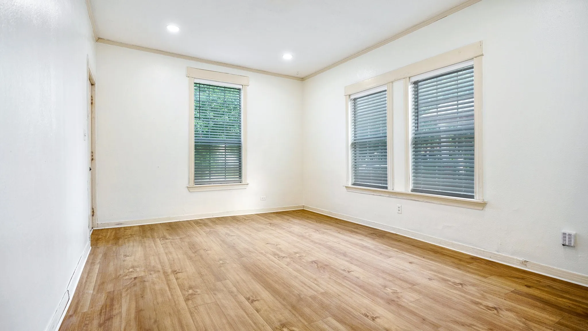 Wood-finish flooring throughout, recessed ceiling lighting, and multiple windows with blinds