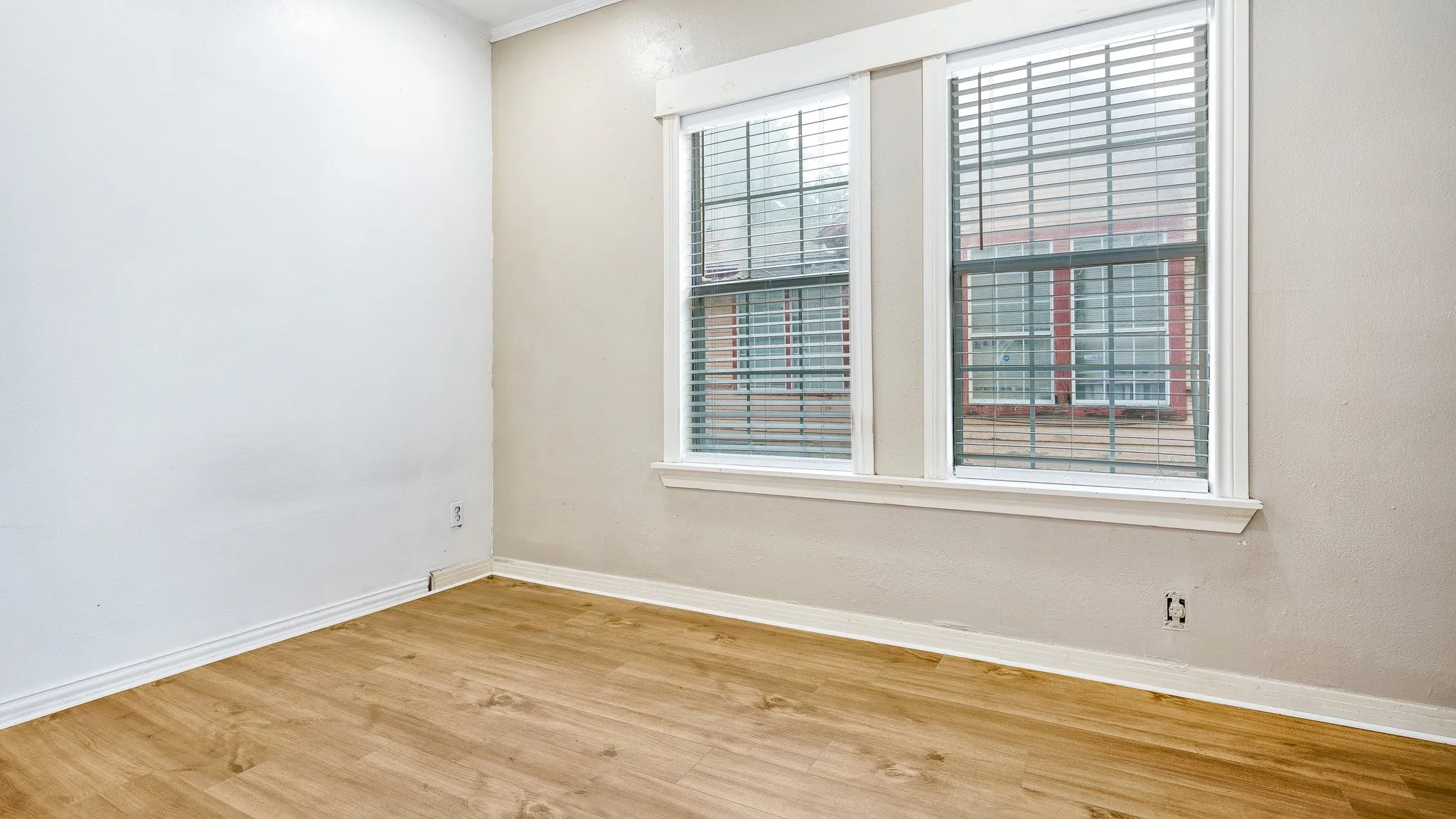Wood-finish flooring, white baseboards, and dual windows with blinds