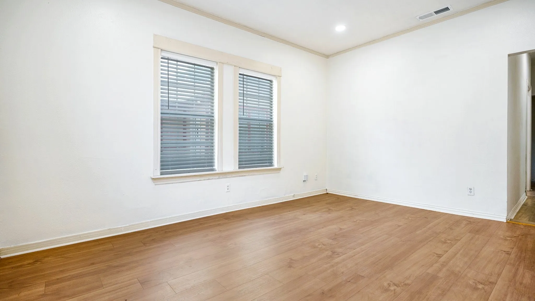 Expansive room featuring wood-finish flooring and two large windows
