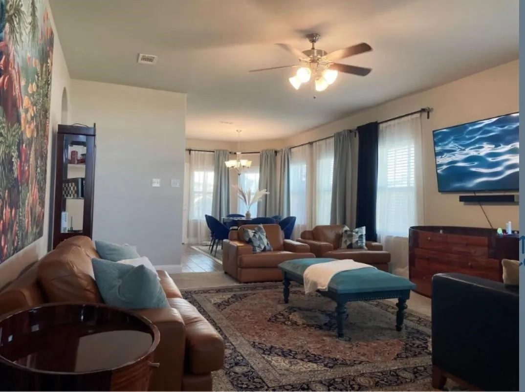 Living area featuring a ceiling fan with integrated lighting, multiple windows with blinds, and an arched entryway