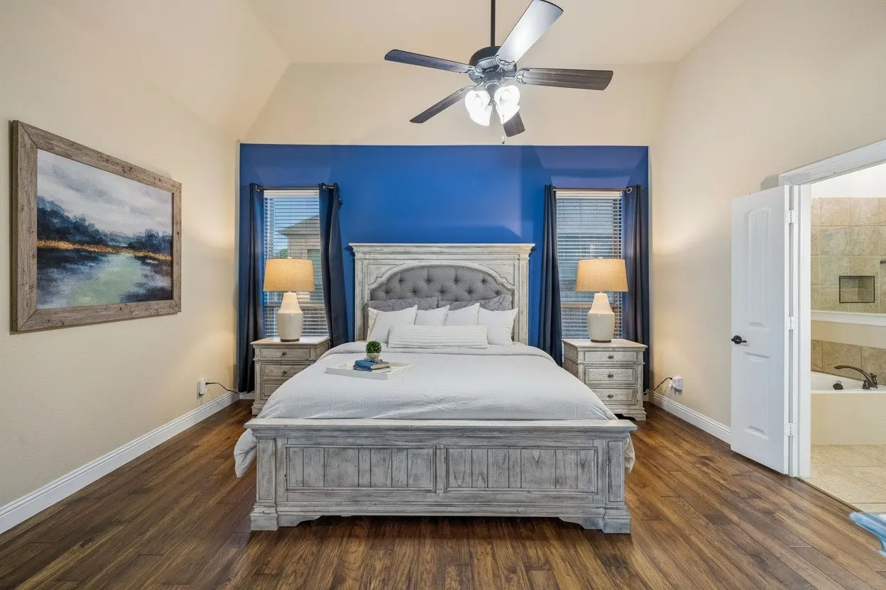 First-floor primary bedroom features wood flooring, generous proportions, updated lighting and an ensuite bath.