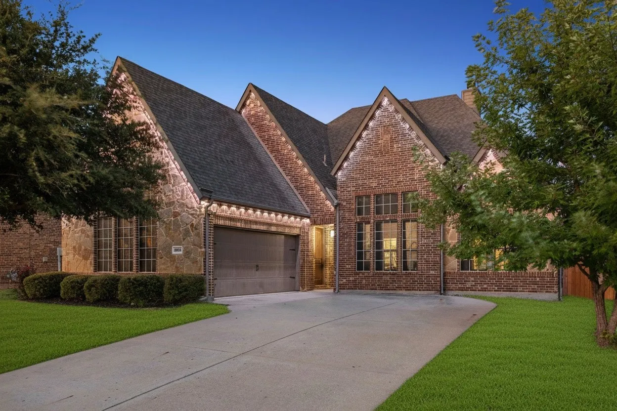Twilight curb appeal highlights the home's brick and stone exterior, front-entry garage and permanent Govee outdoor lighting.