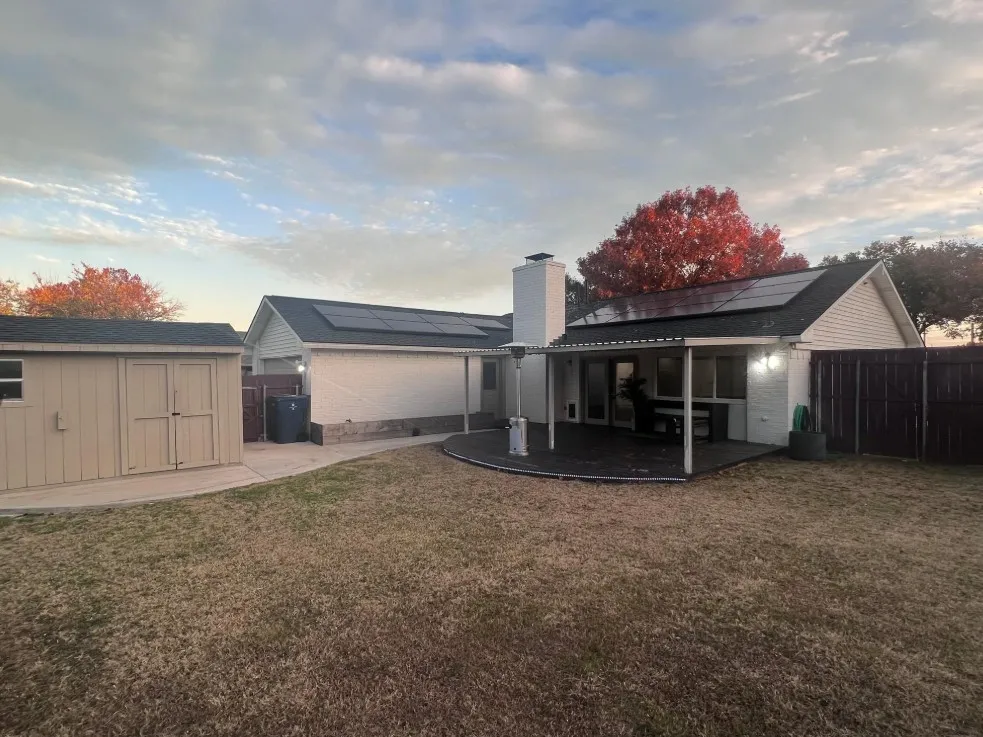 Rear exterior featuring a covered patio, solar panel array, storage shed, and privacy fencing