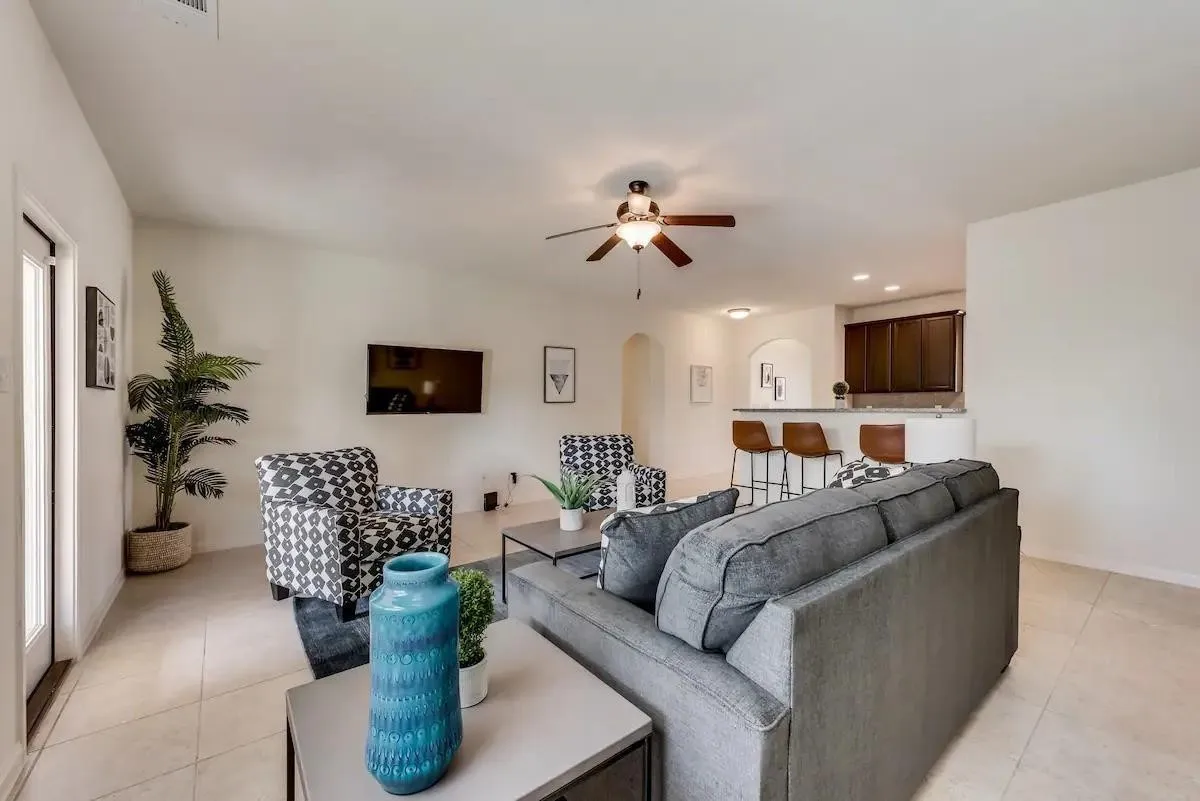 Recessed lighting illuminates an open-concept living area with a ceiling fan