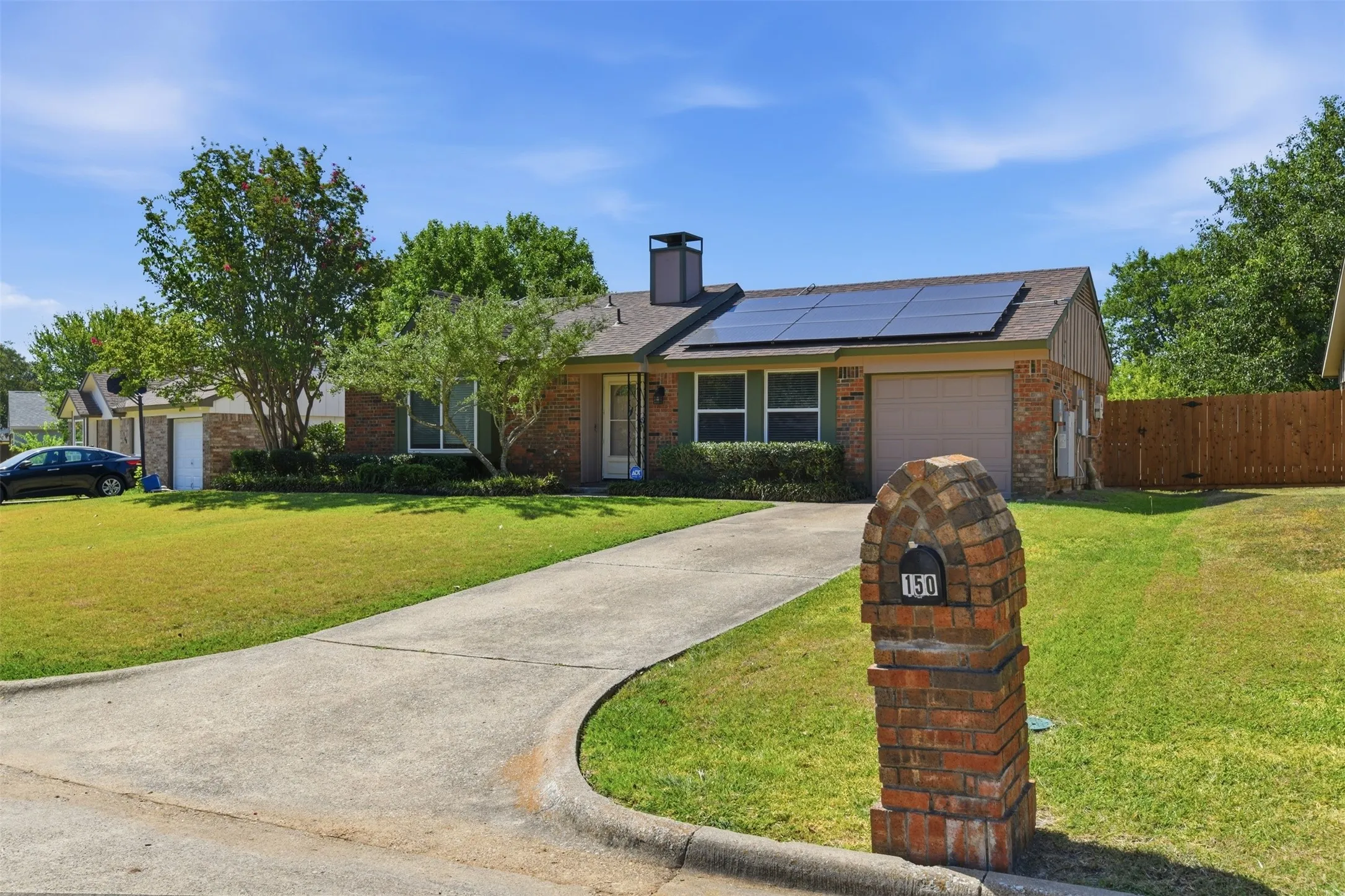 Brick exterior with solar panels, an attached garage, and a concrete driveway