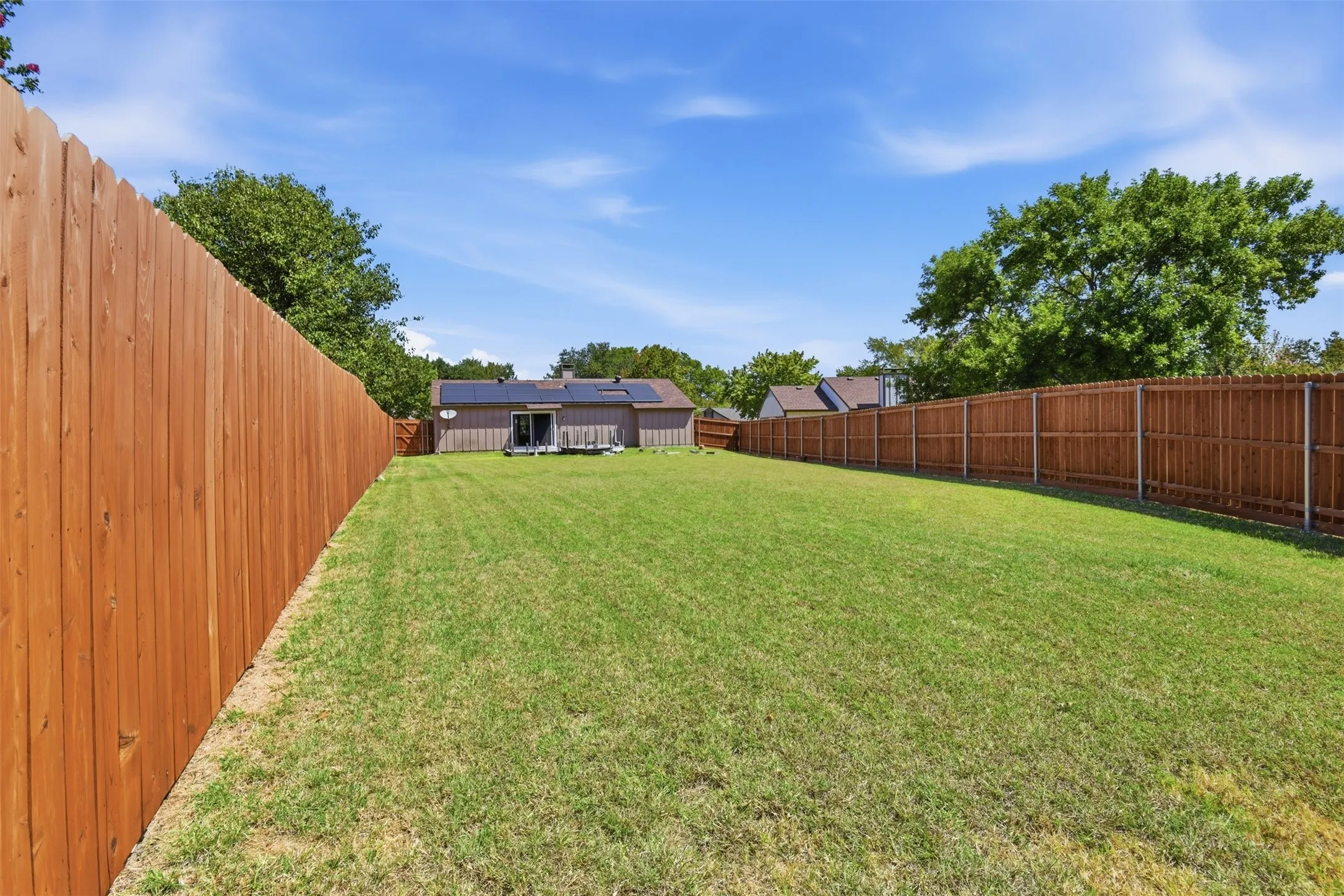 Expansive backyard featuring a manicured lawn and tall wood privacy fencing